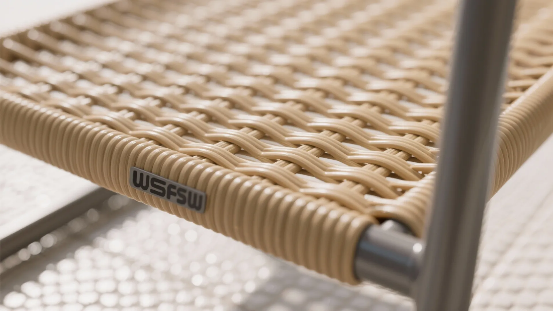 Macro of synthetic rattan over powder-coated aluminum beside slip-textured porcelain tile.