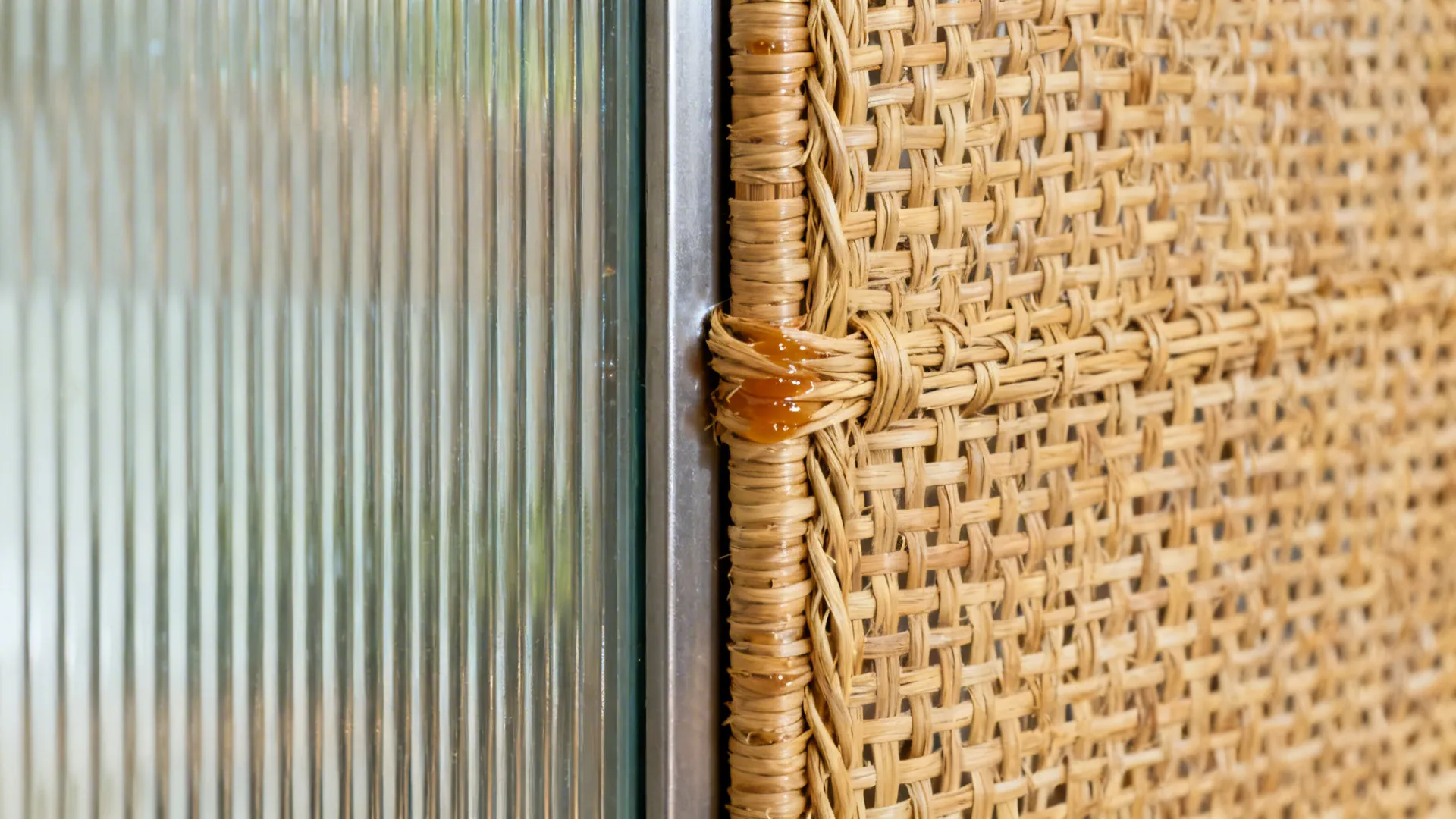 Macro of rattan-wrapped frame junction with reeded glass ribs.