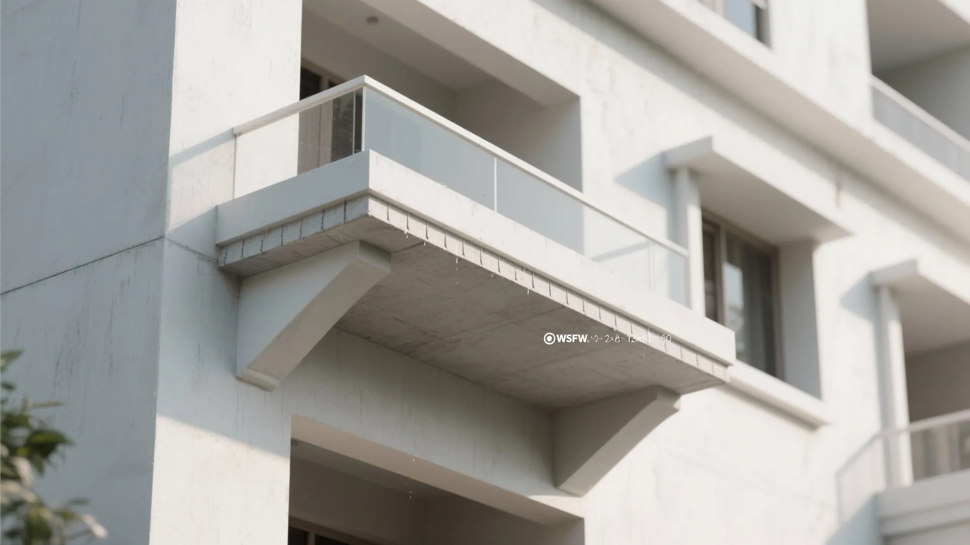 Modern white building exterior featuring a concrete balcony with glass railings and simple window designs