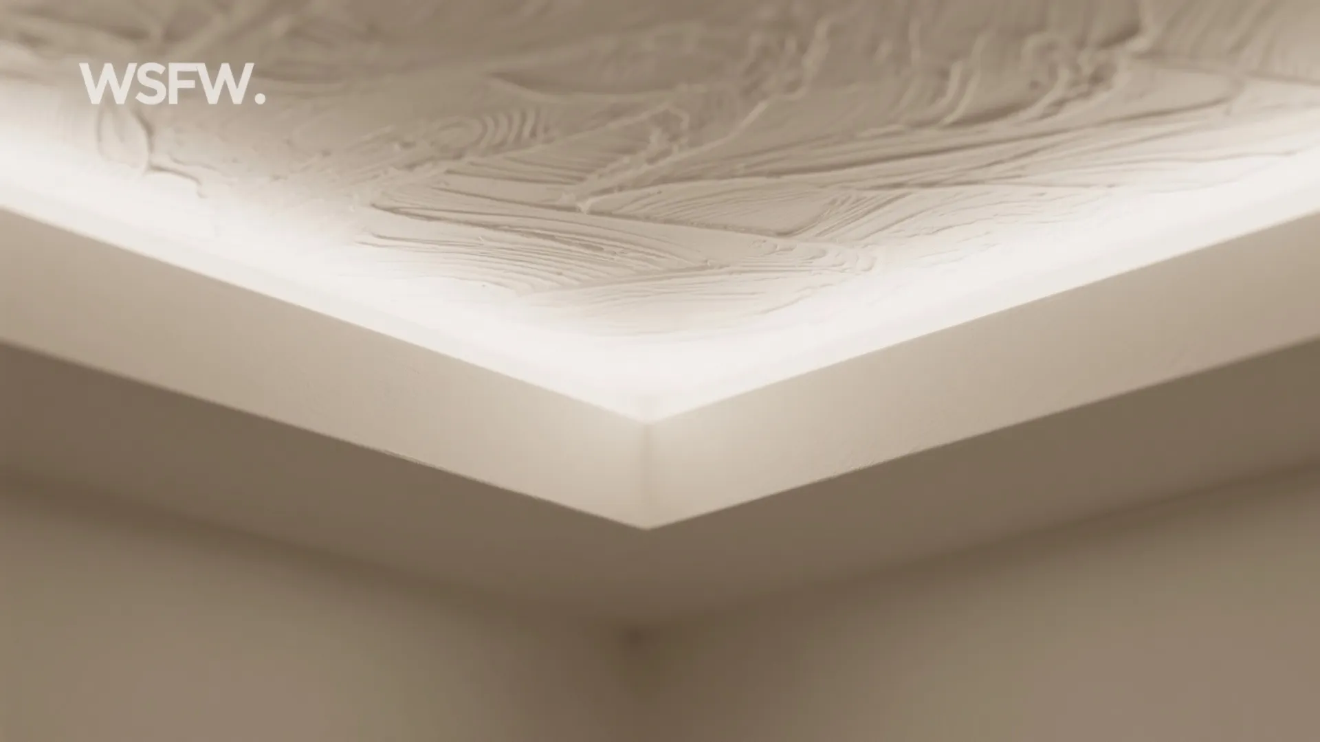 Detailed view of textured white ceiling surface with bright hidden light strip along the edge
