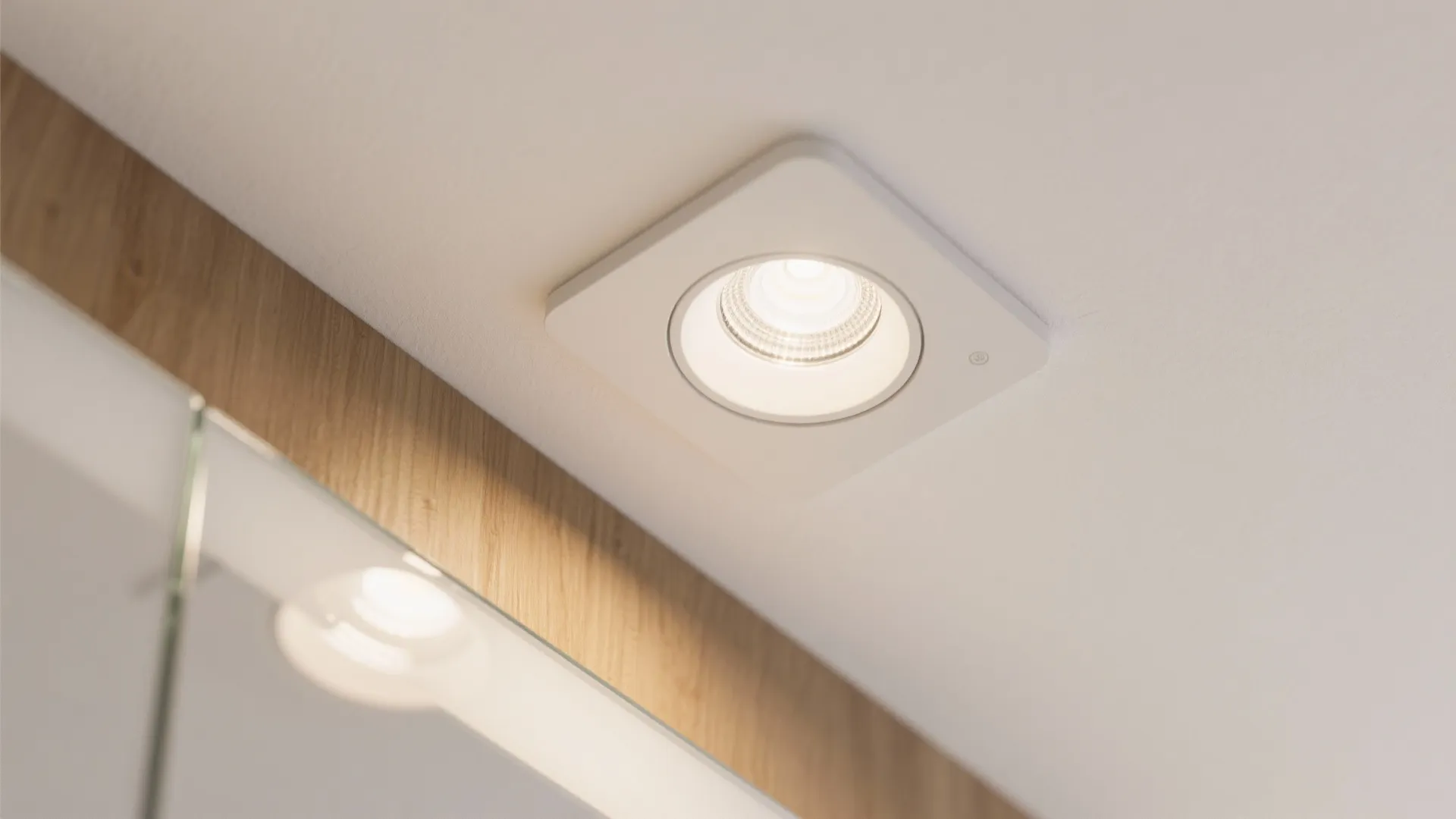Close up of a square white ceiling light fixture with soft glow on white ceiling surface