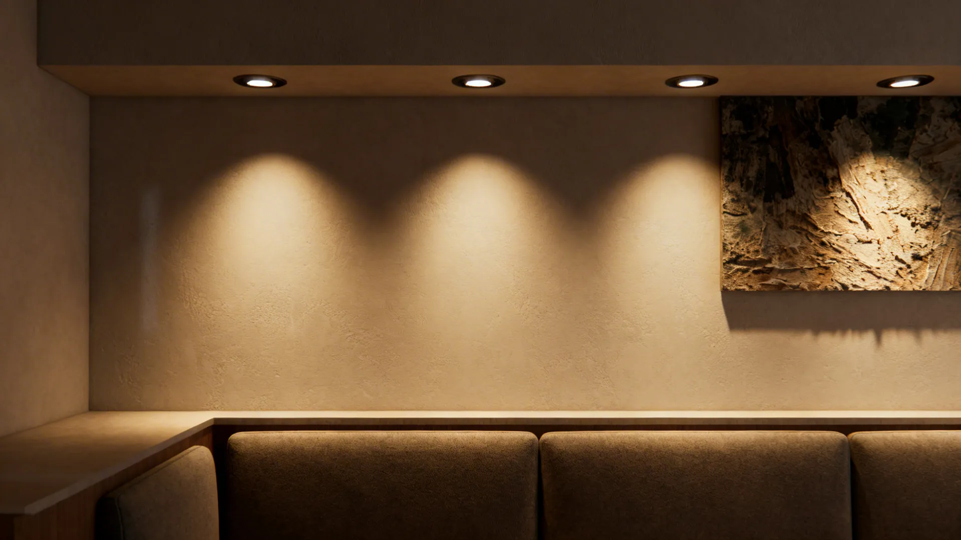 Staggered recessed downlights with a warm wall washer highlighting textured art