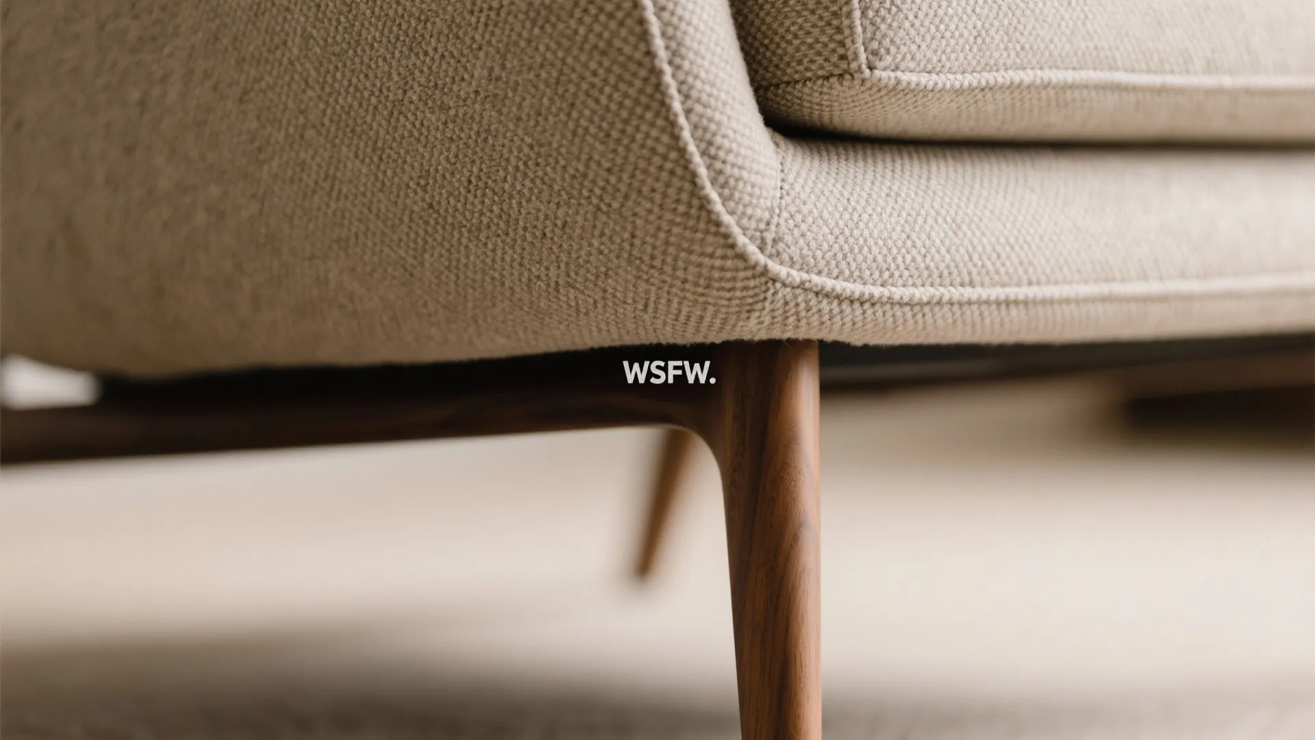 Macro of recliner stitching and tapered wooden leg with performance fabric texture.