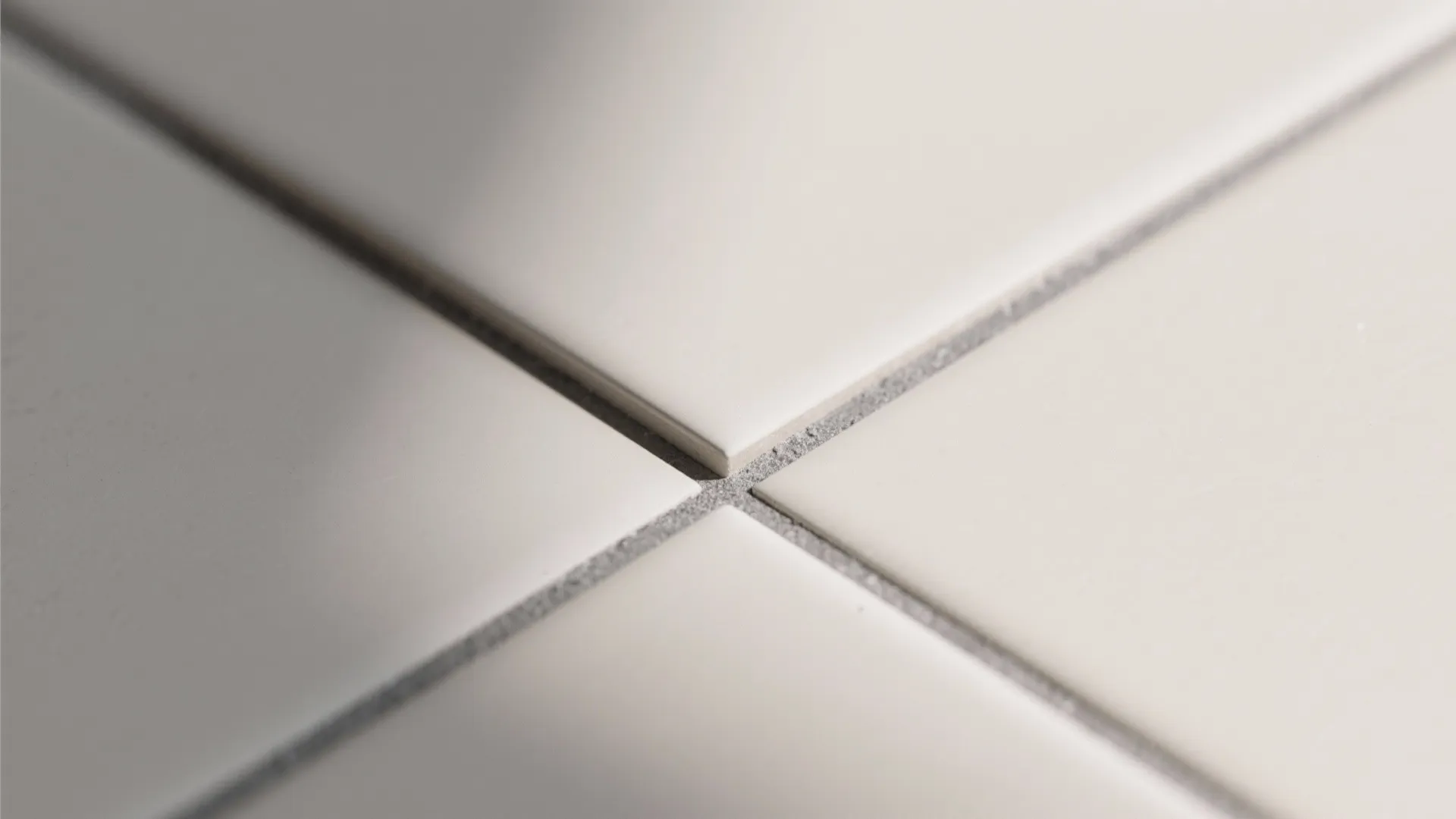 Close up view of white square floor tiles with grey grout lines in a simple pattern