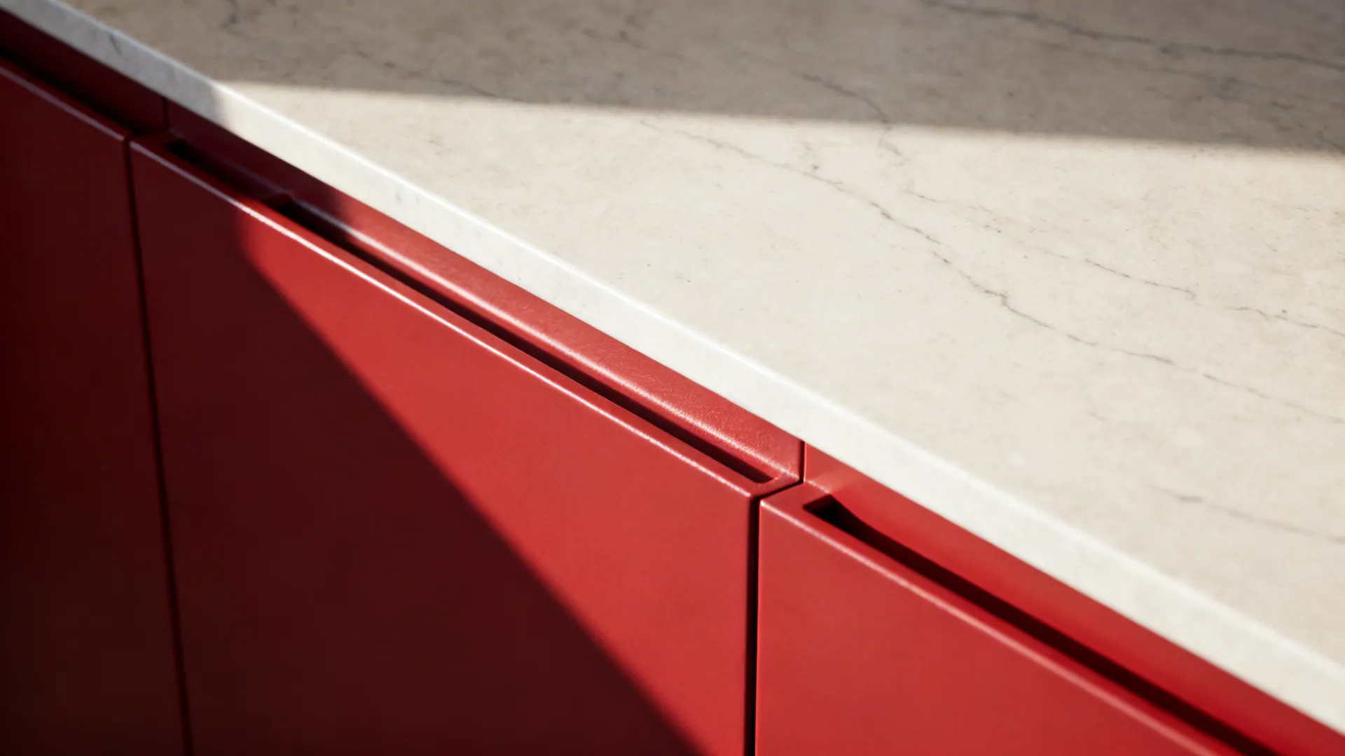 Macro detail of matte red cabinet edge and integrated pull with quartz countertop