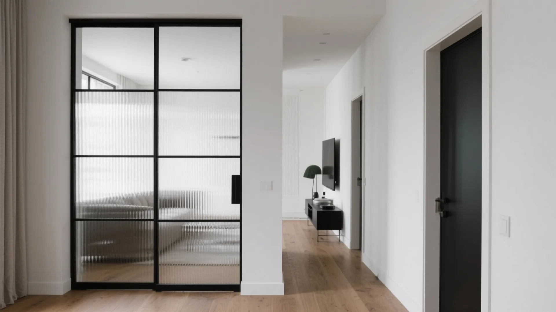 Black framed glass sliding doors separating hallway from living room area with wooden floor boards