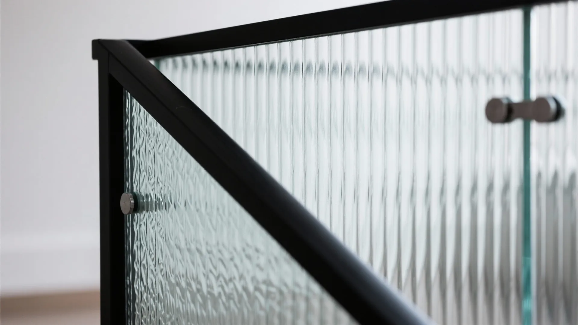 Close up view of a black metal frame with textured glass panels for a modern railing