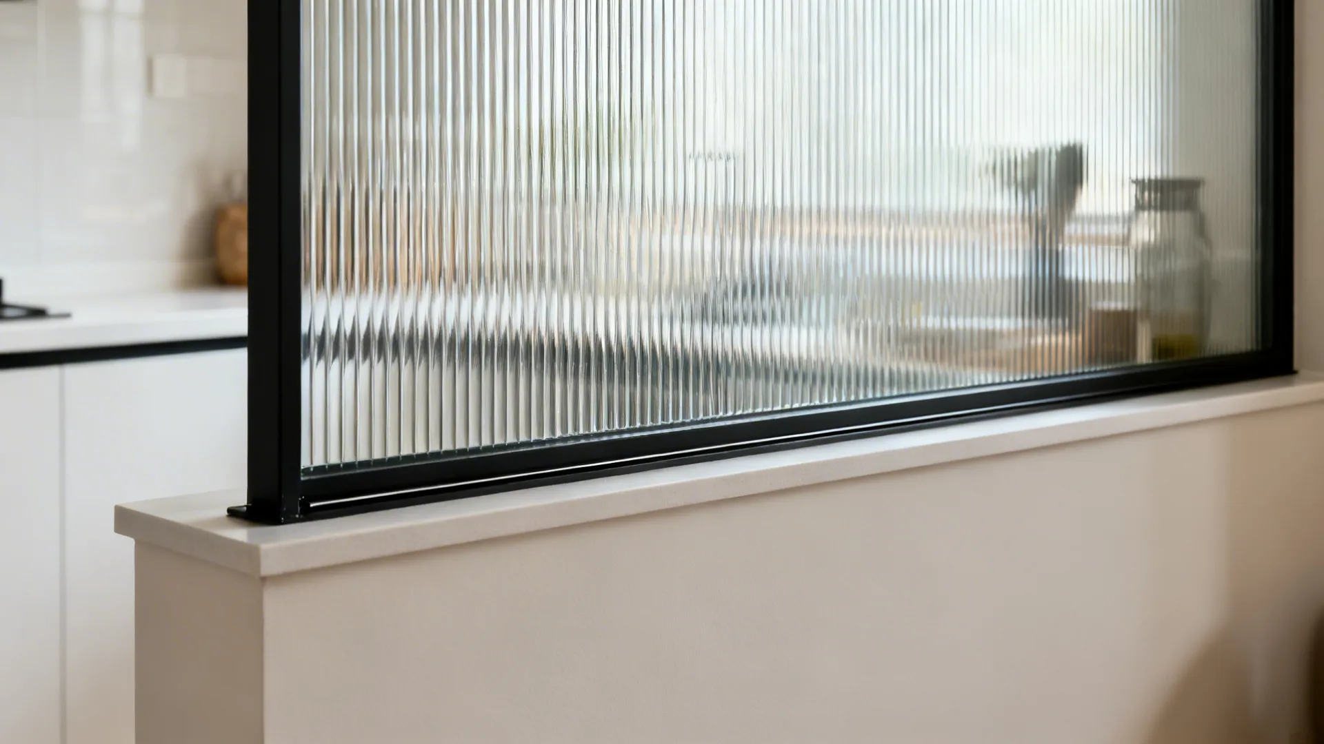 Close-up of reeded tempered glass in a slim black frame atop a half wall