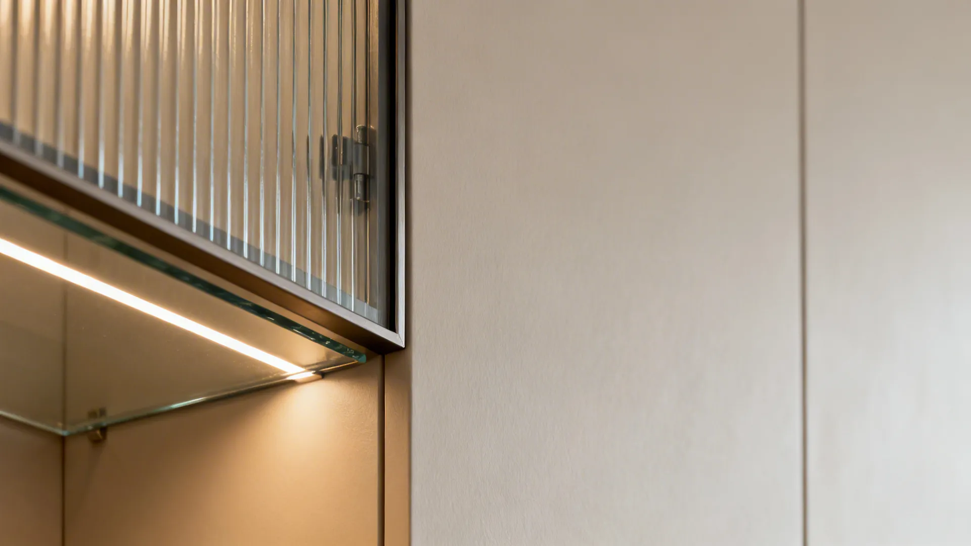Close-up of reeded glass corner cabinet door with LED-lit shelf inside.