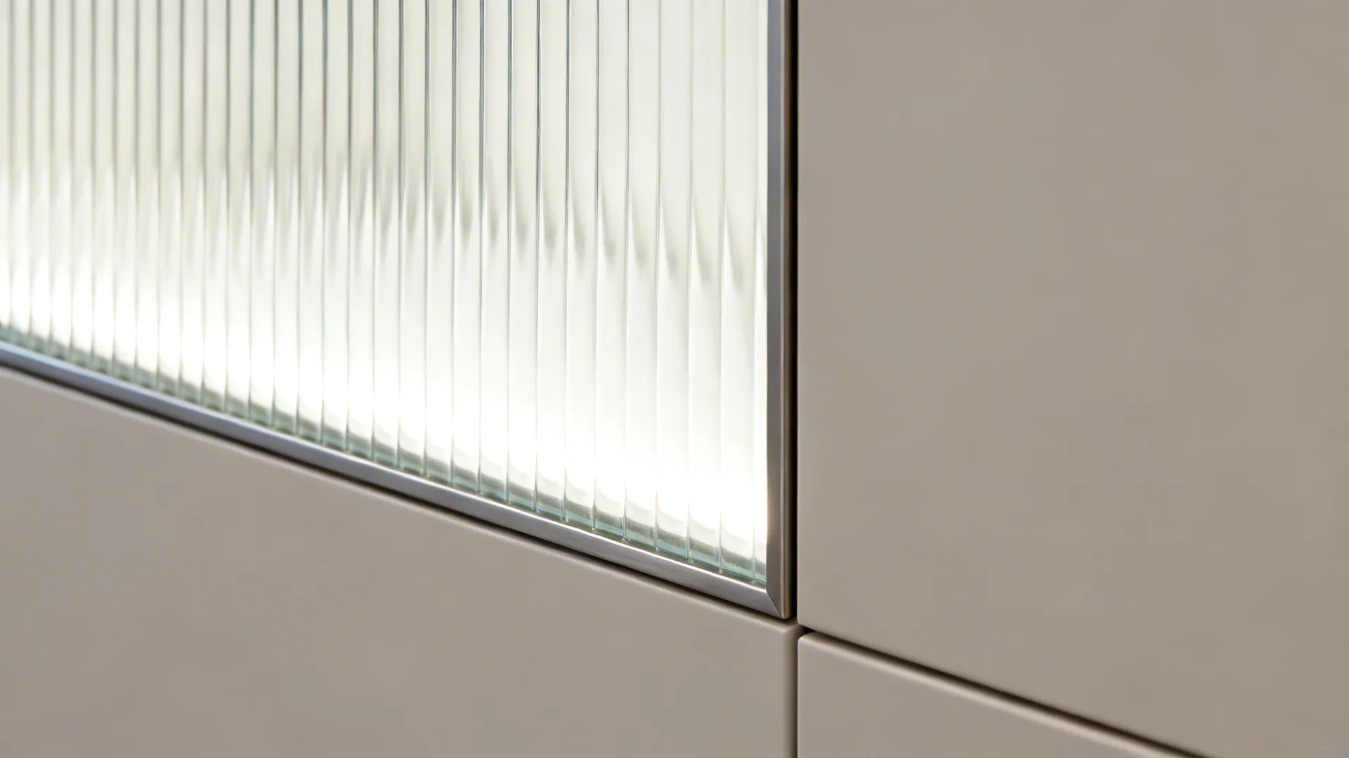 Close-up of reeded glass door with slim metal frame and glowing white interior.