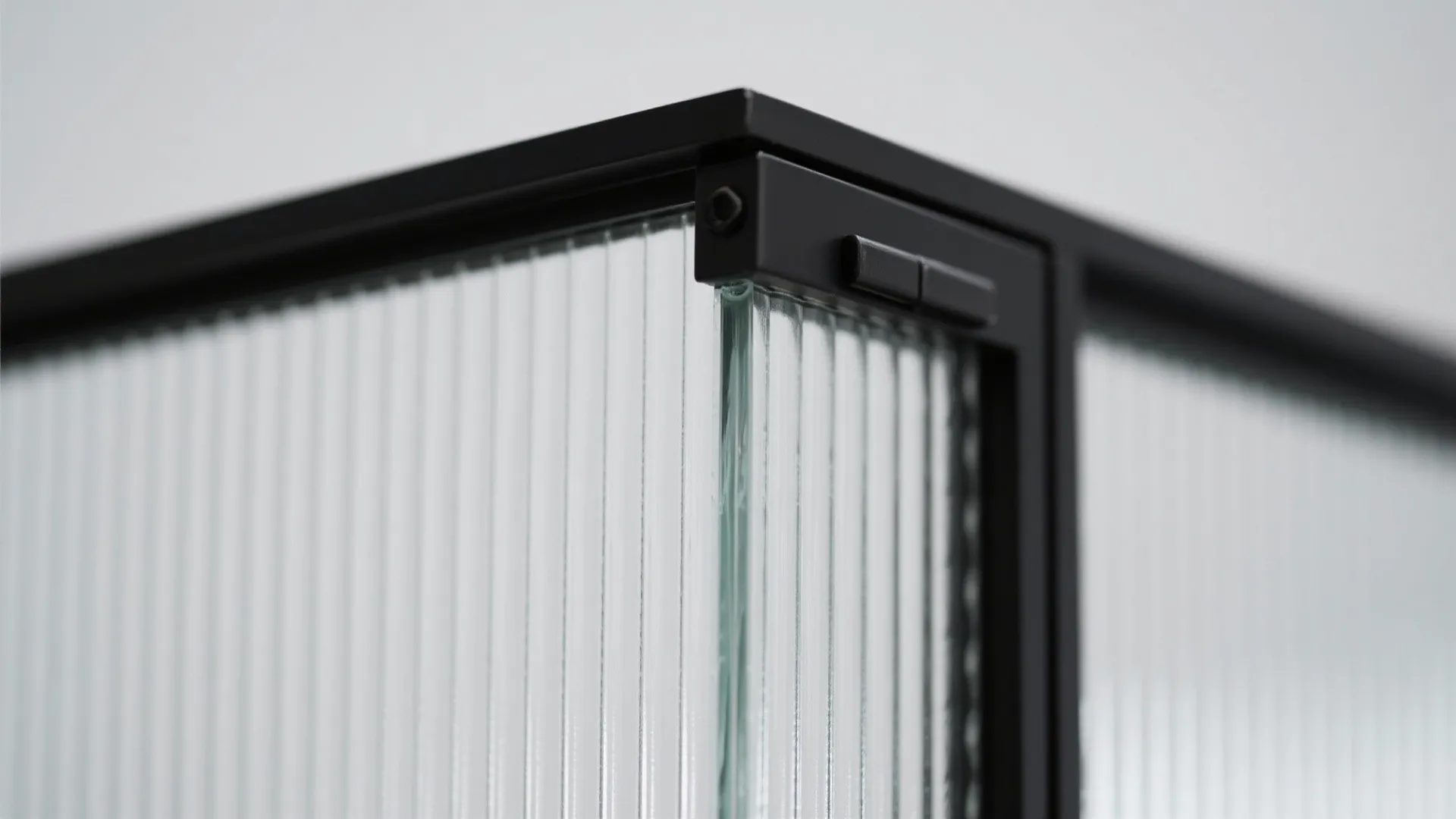 Macro of reeded glass ribs and powder-coated black frame corner with hinge detail.