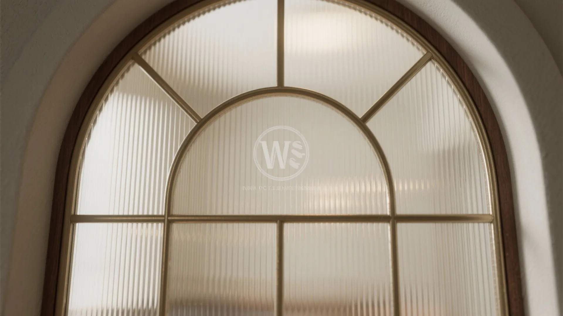 Arched window featuring textured glass panels and golden metal frames in a bright and sunny room