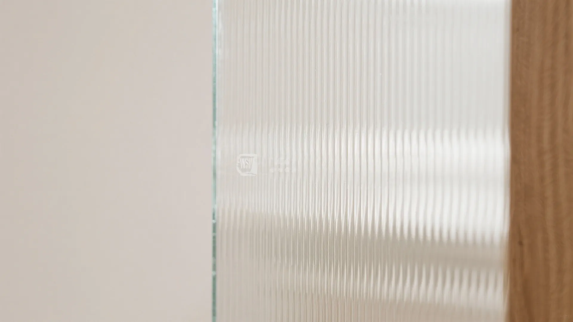 Close up view of textured vertical lined glass panel next to a light brown wall