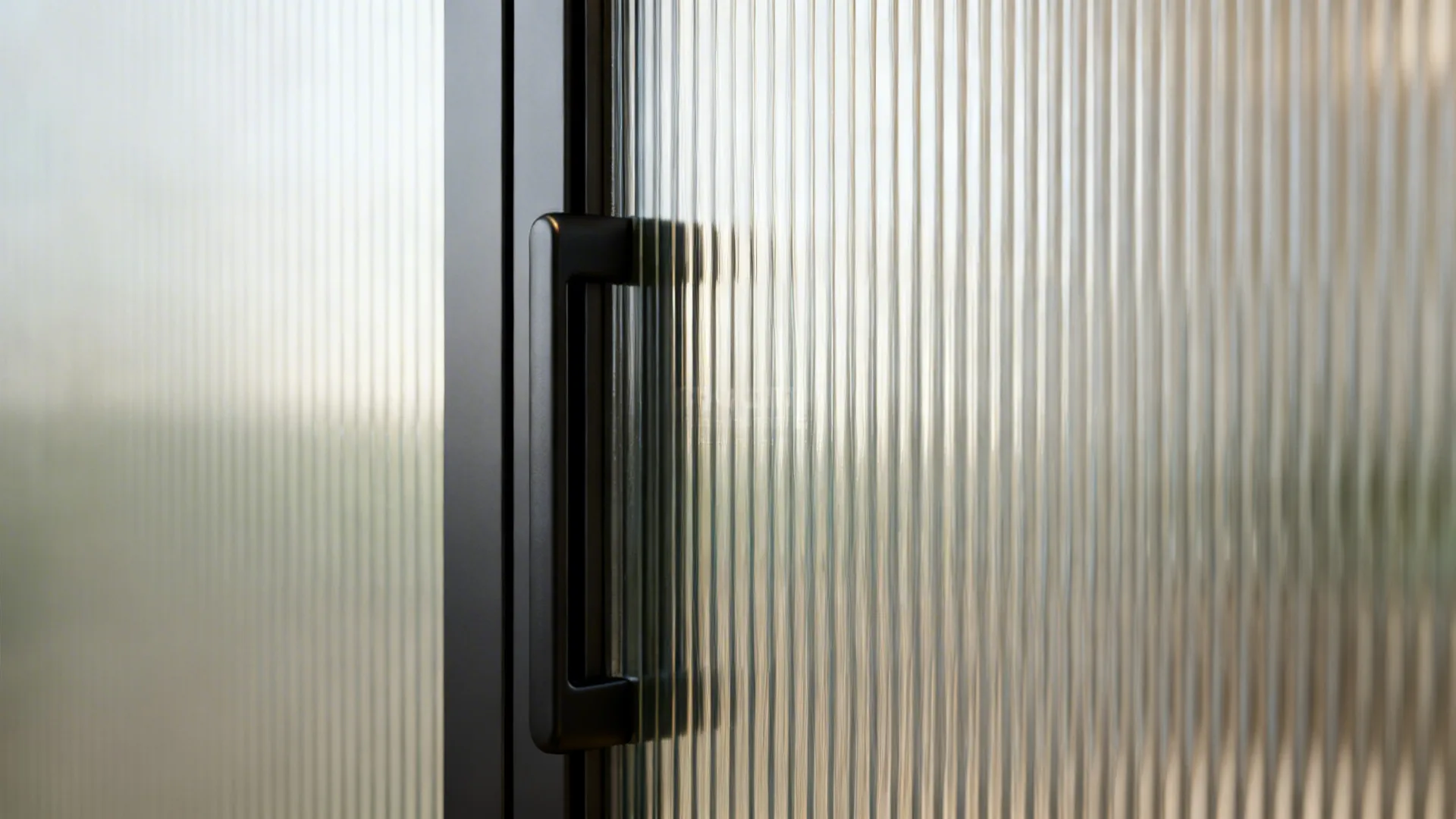 Macro detail of reeded glass and matte black sliding door hardware with smooth track.
