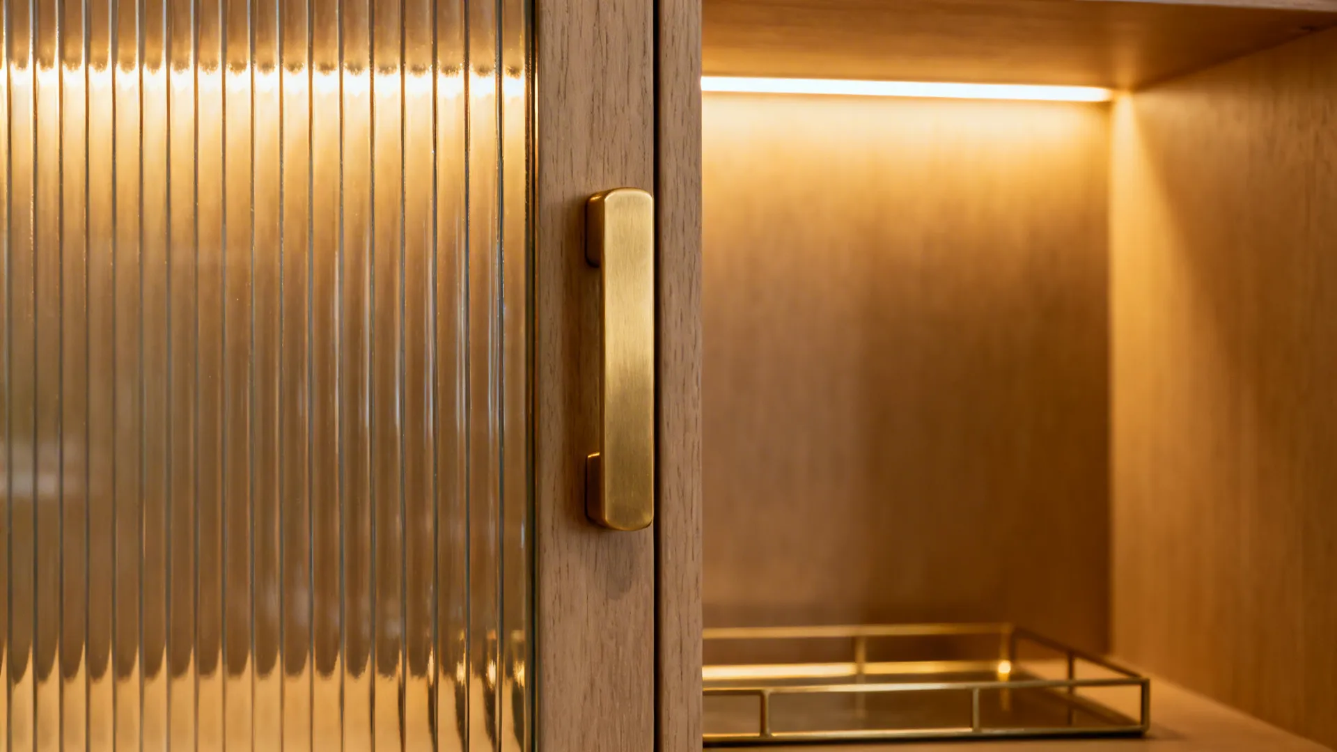 Close up of wooden cabinet with textured glass door and a gold handle with light inside