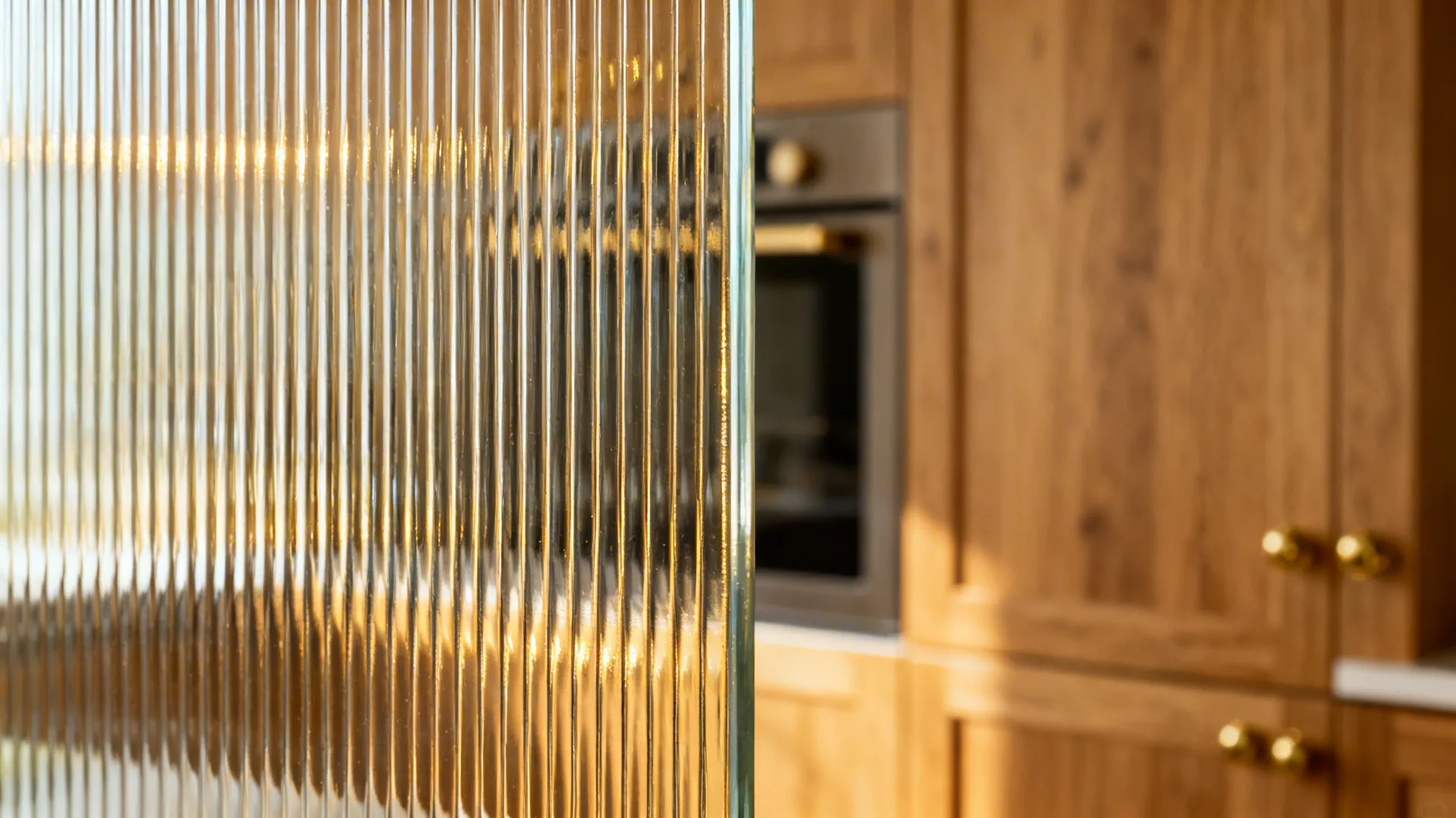 Macro detail of reeded glass flutes with warm kitchen tones behind.