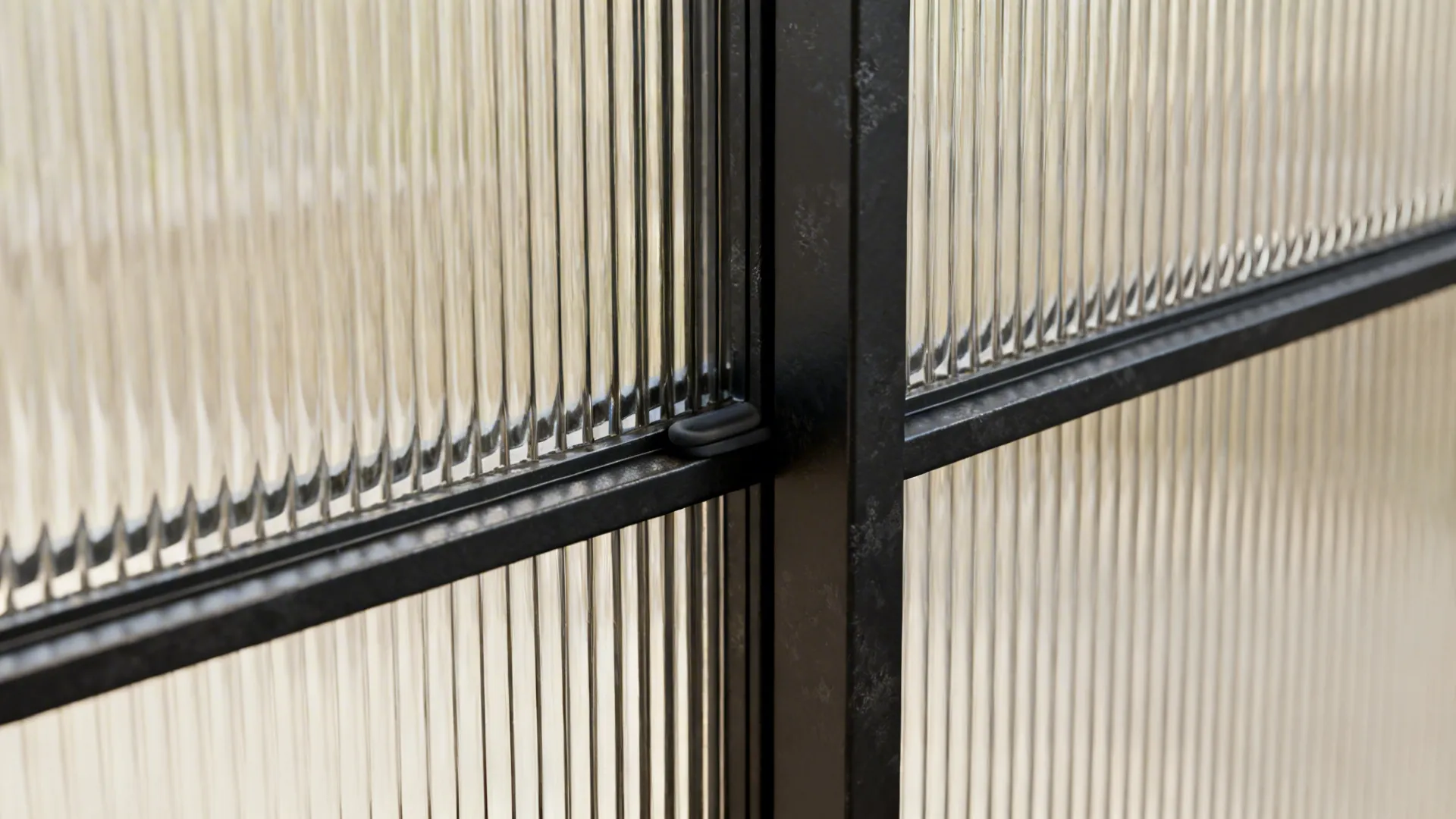 Macro of black steel mullion and reeded glass with sliding track and seal detail in soft daylight.