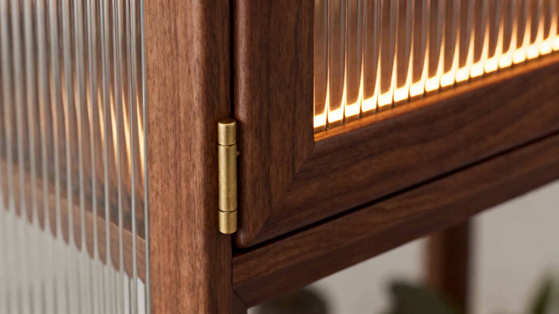 Close-up of walnut frame corner with reeded glass and brass hinge detail.