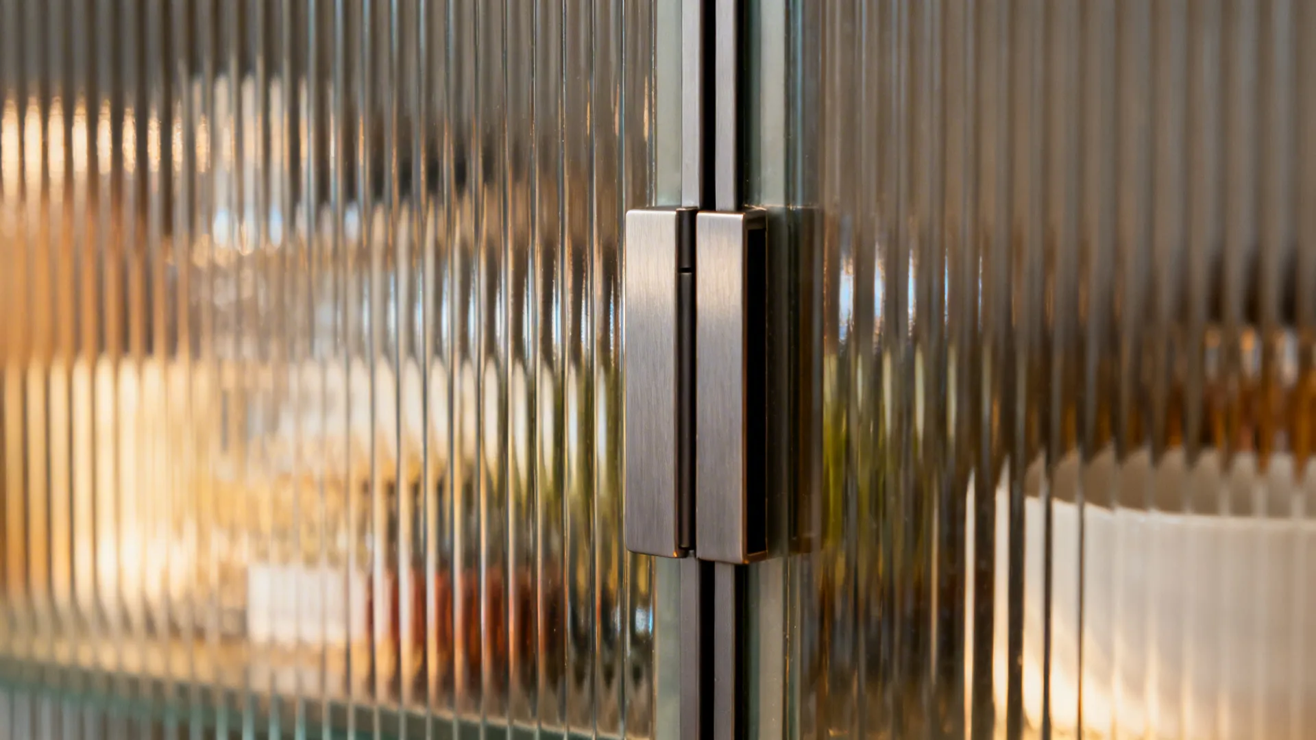 Macro of reeded glass cabinet door with warm light revealing ribbed texture.