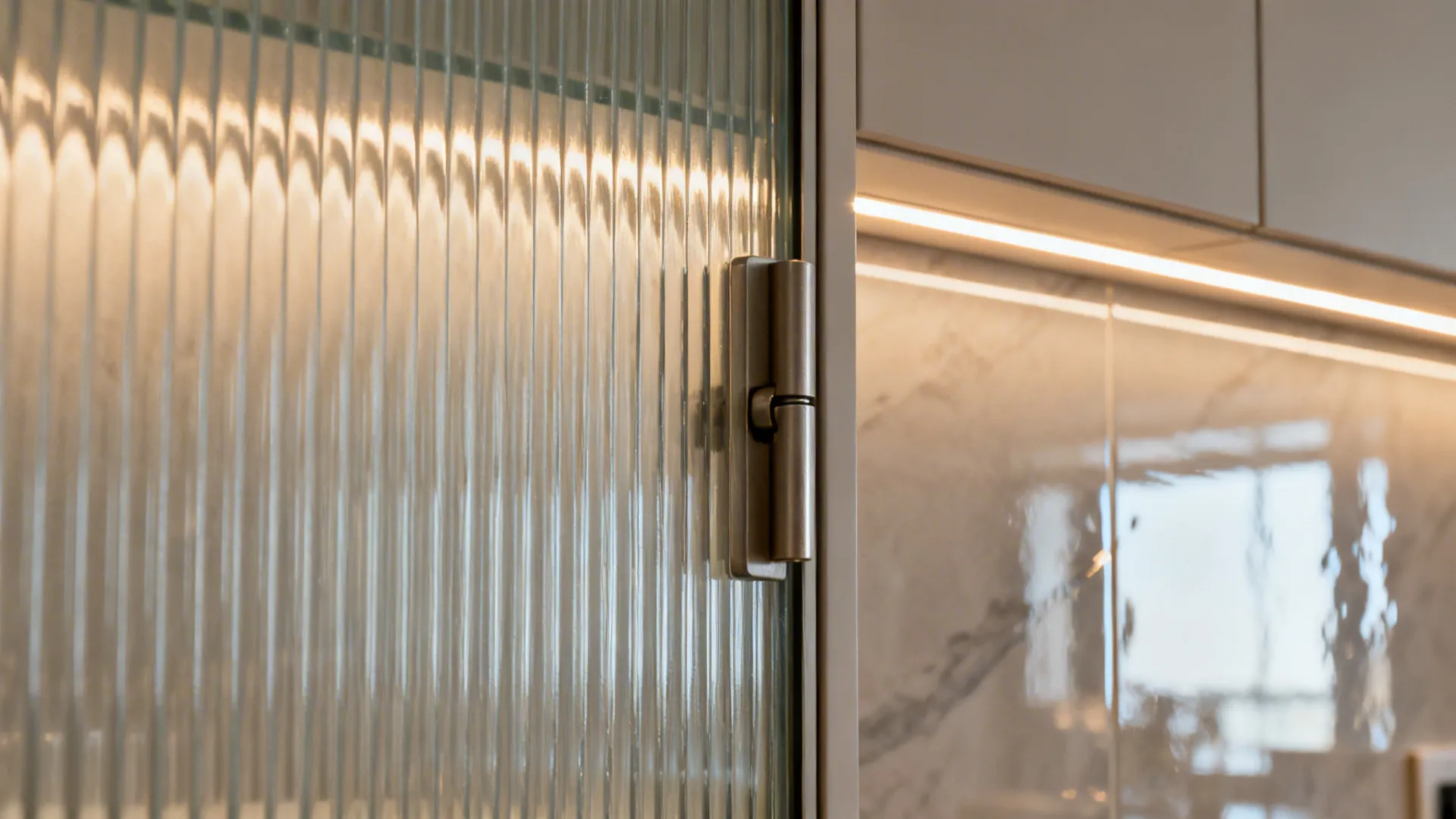 Close-up of reeded glass cabinet door glowing with warm LED light and fine hardware.