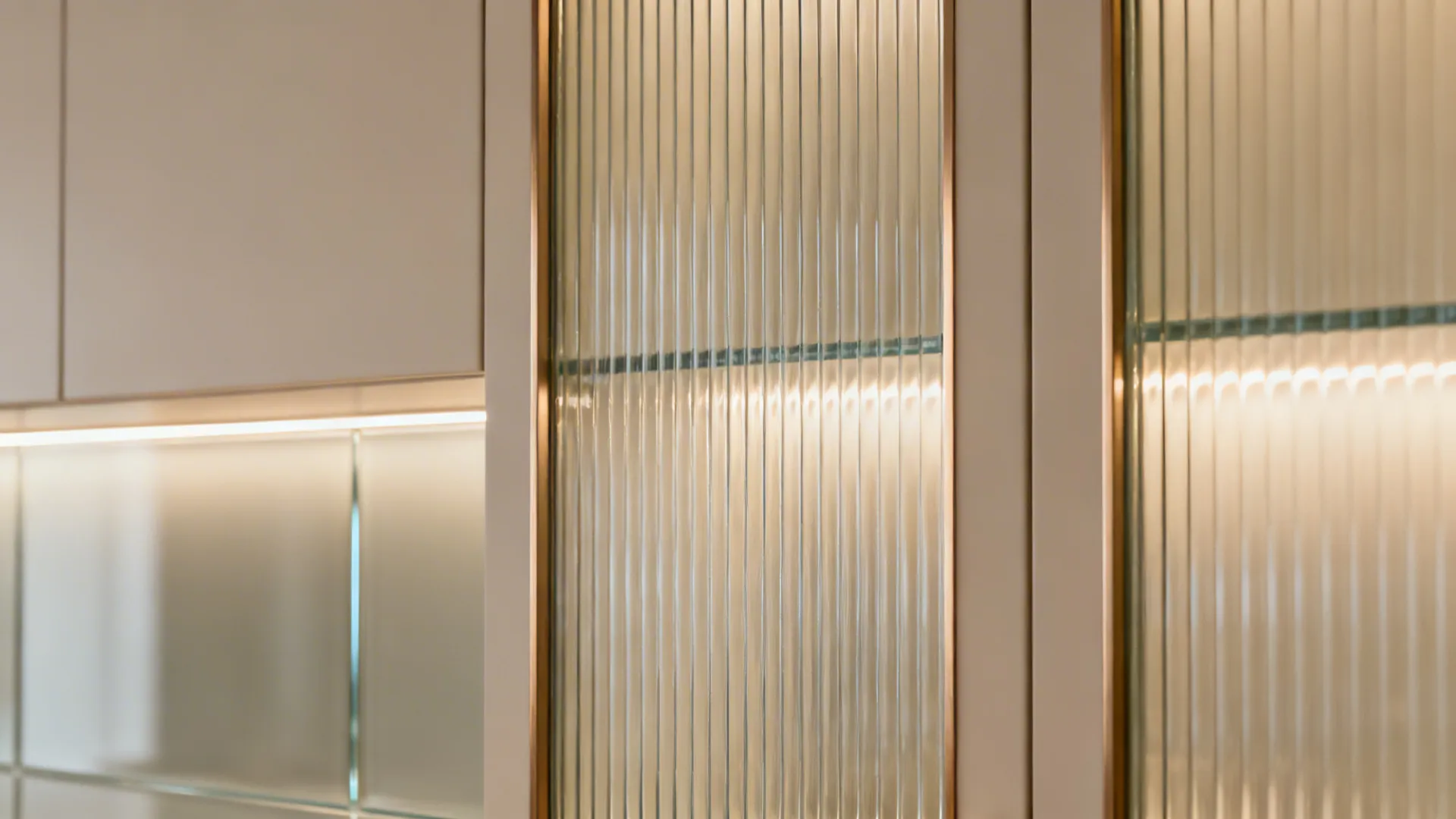 Macro of reeded glass cabinet and satin glass backsplash under diffused light.