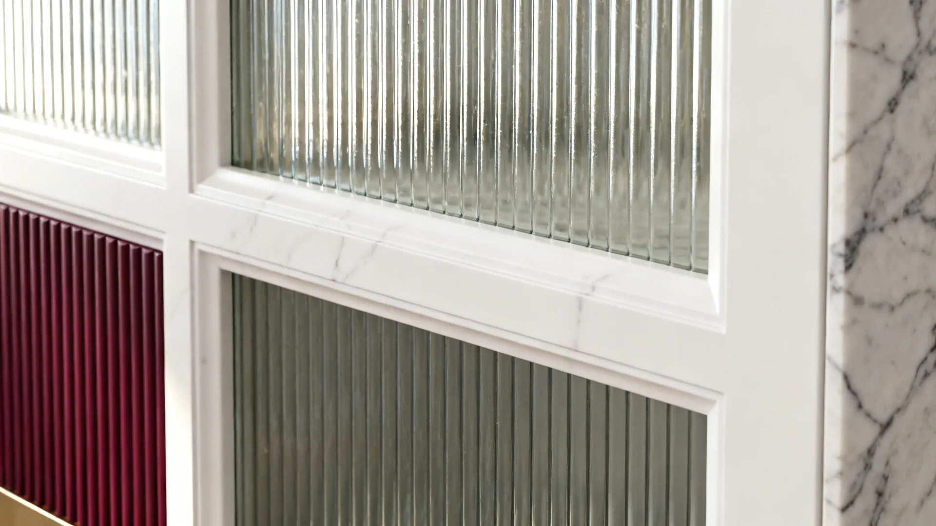 Close-up of reeded glass in a white frame beside a ribbed burgundy panel and quartz.