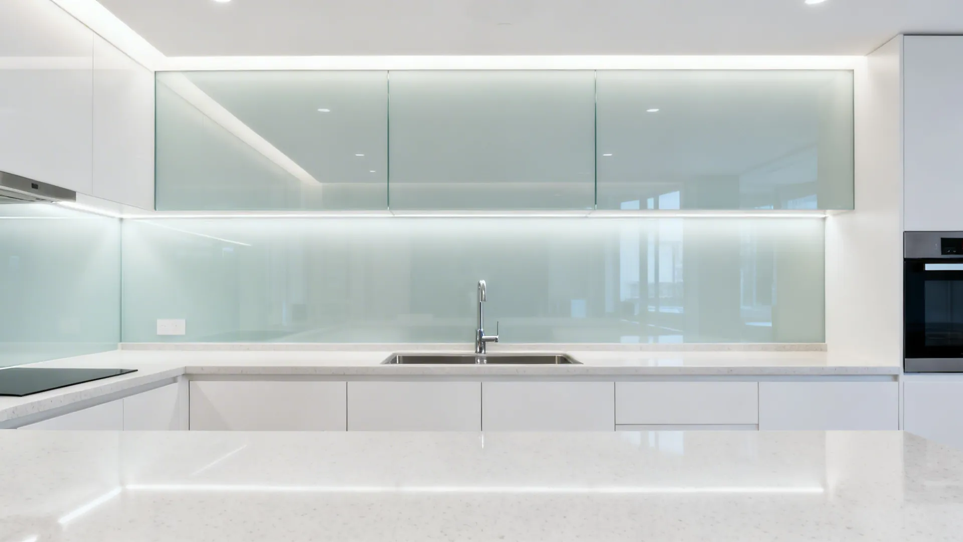 Pale low-iron glass backsplash reflecting layered lighting under a satin POP ceiling.