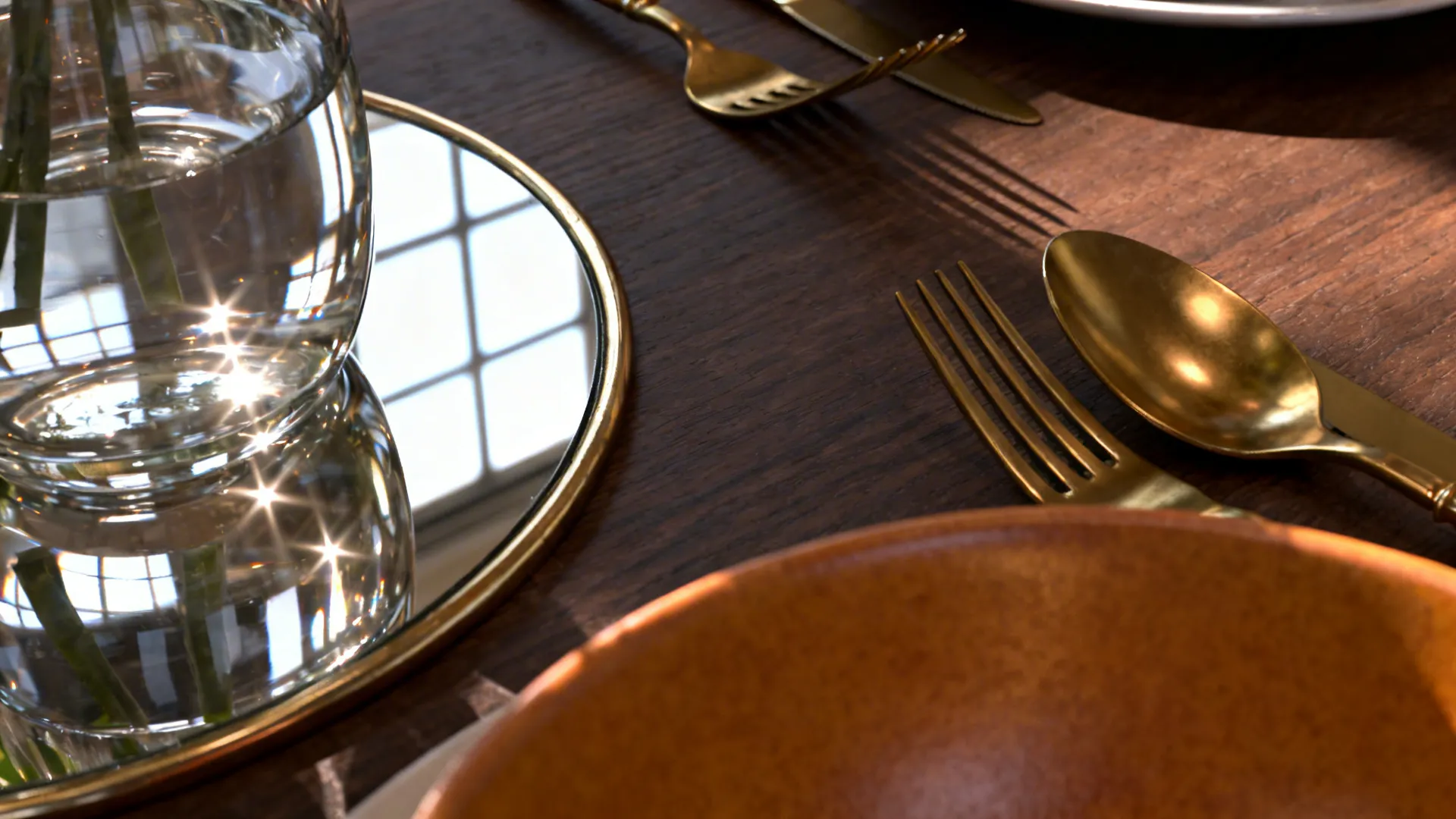Close-up of brass flatware, glass vase, and mirror reflections on a dark brown table.