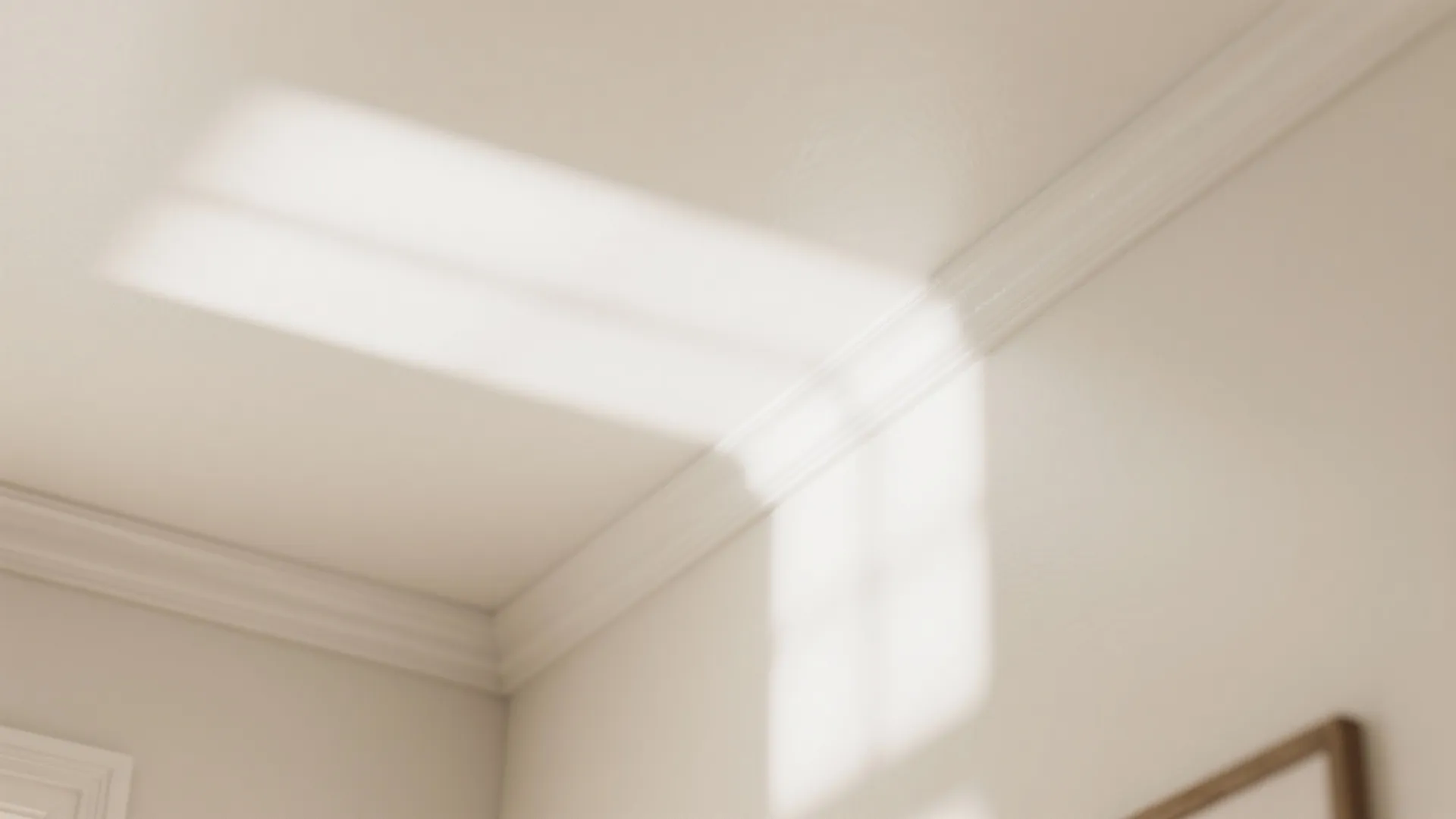 Bright sunlight reflecting from a window onto a beige wall and ceiling with white wall panel