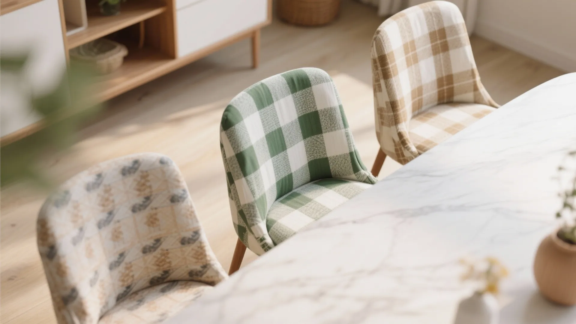 Three dining chairs with different patterned fabric covers arranged around a large white marble table