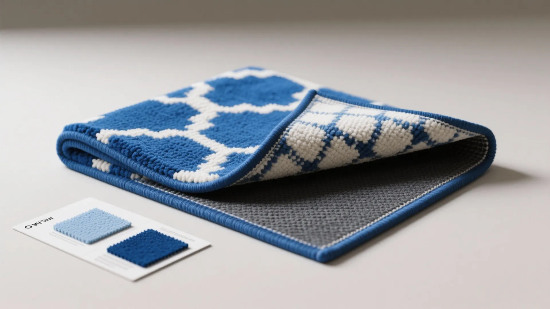 Blue and white patterned reversible rug showing texture with fabric color samples on grey surface