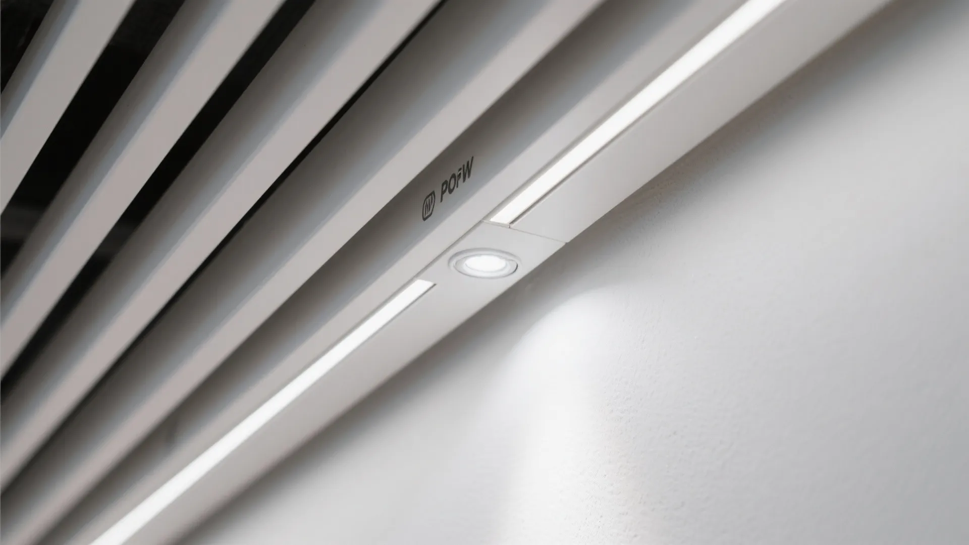 Detailed view of linear ceiling light and wall light fixture installed on a white wall