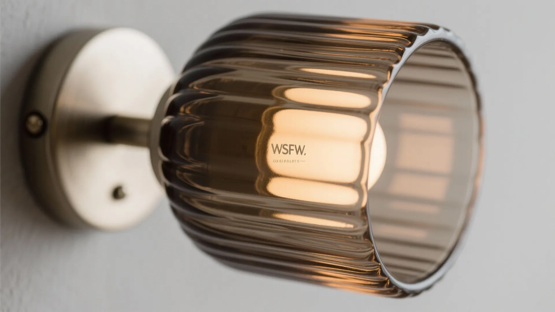 Close up view of a wall light with ribbed brown glass and a gold base