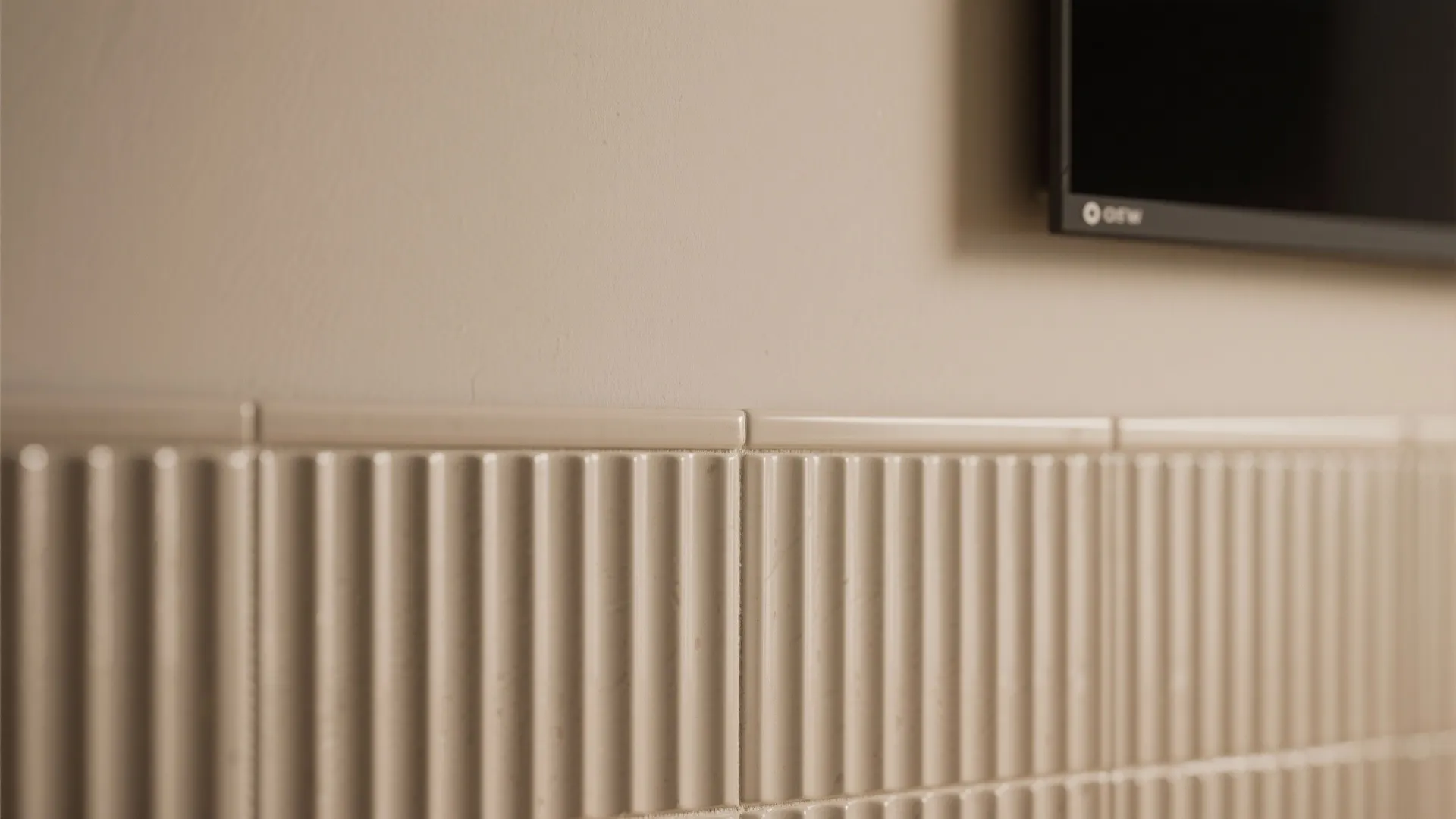 Close up of beige vertical ribbed wall panels installed below a wall mounted black television