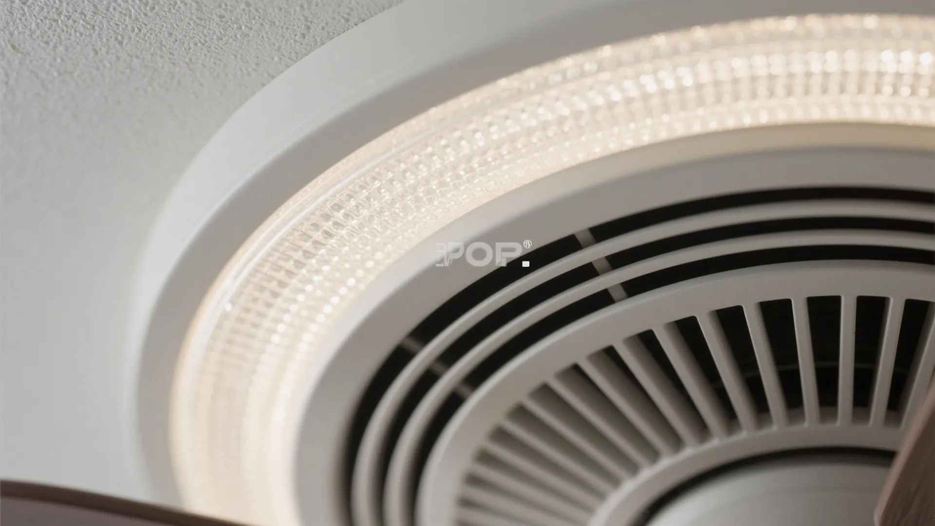 Close up view of a circular white ceiling light fixture showing texture and warm glowing details