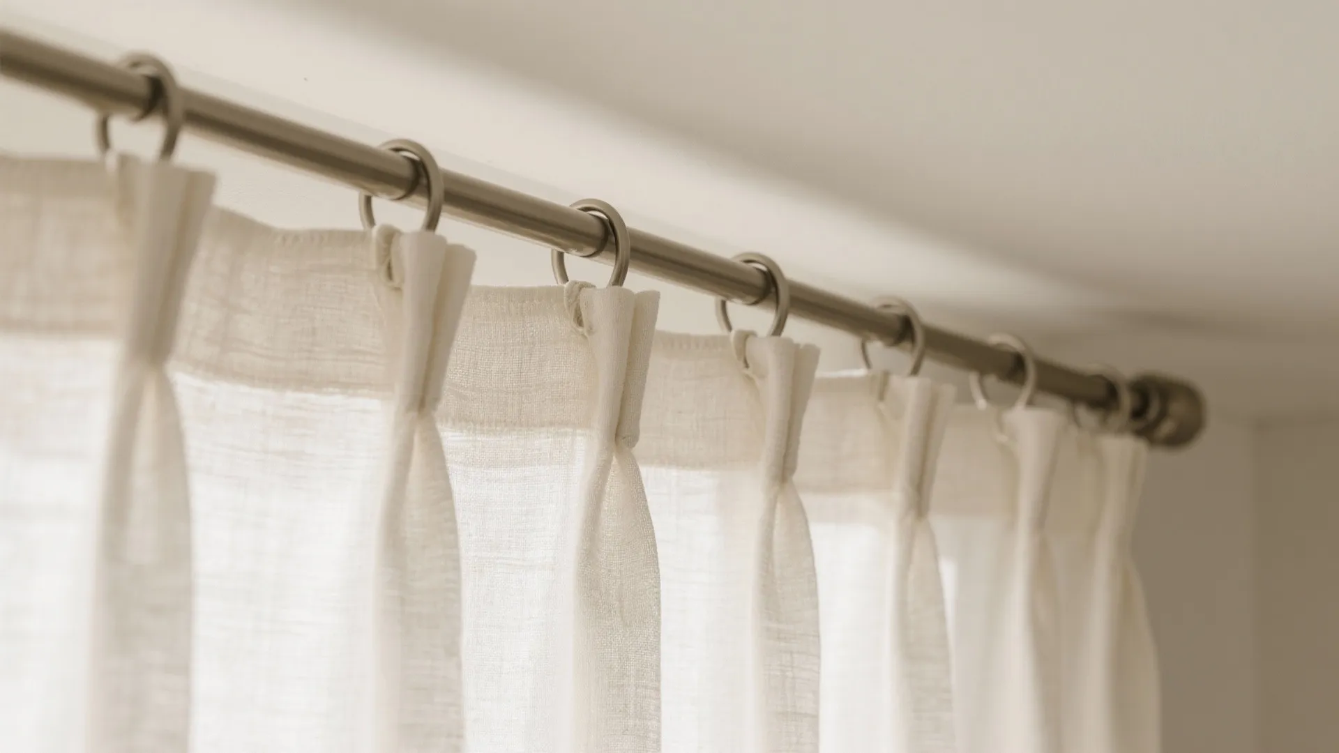 Macro of a ripple-fold curtain header on a low-profile ceiling track with matte linen fabric waves.