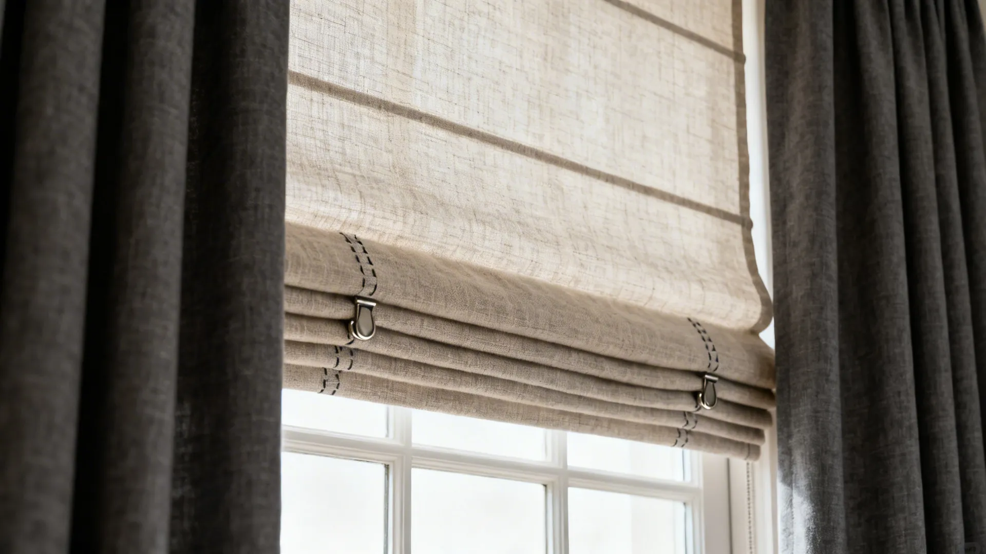 Close-up of linen Roman shade layered with charcoal drapes showing texture and hardware
