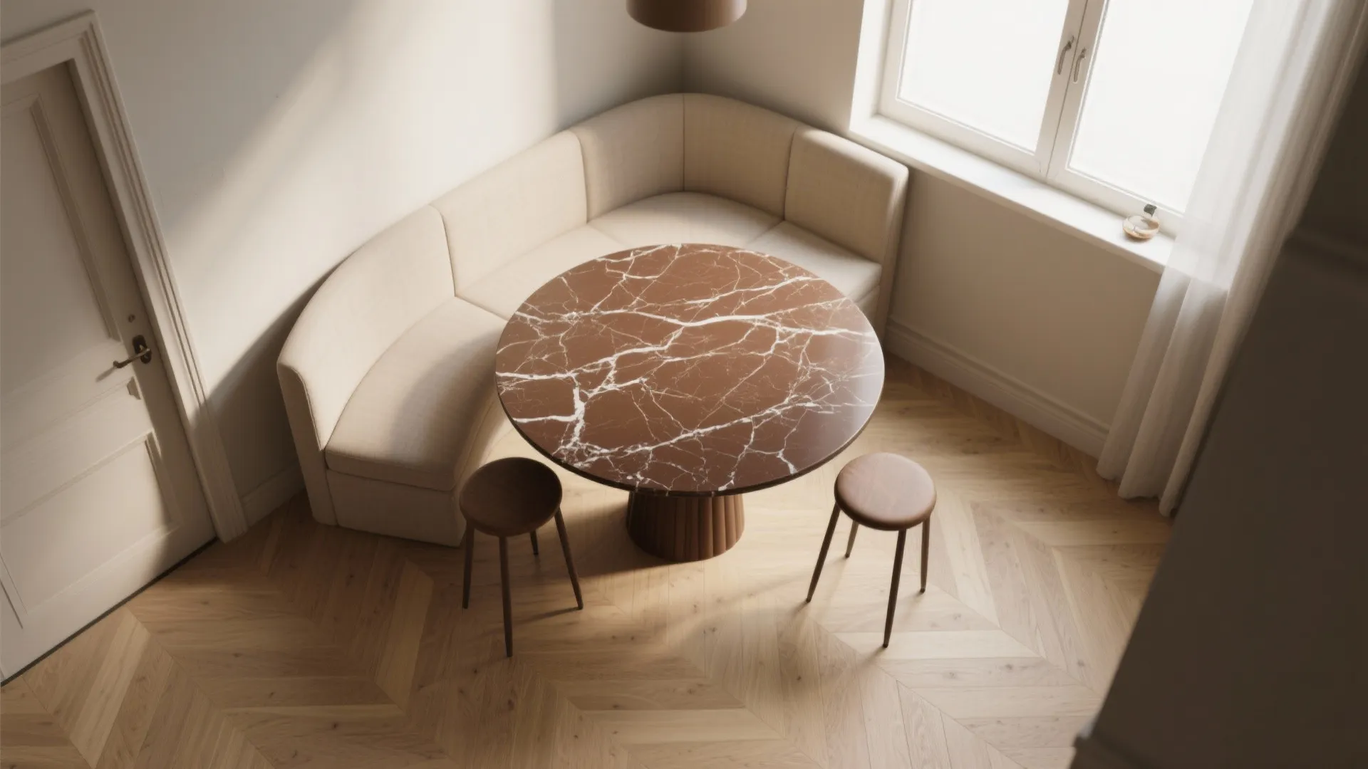 Modern dining area with brown marble round table cream corner sofa wooden floor and natural light