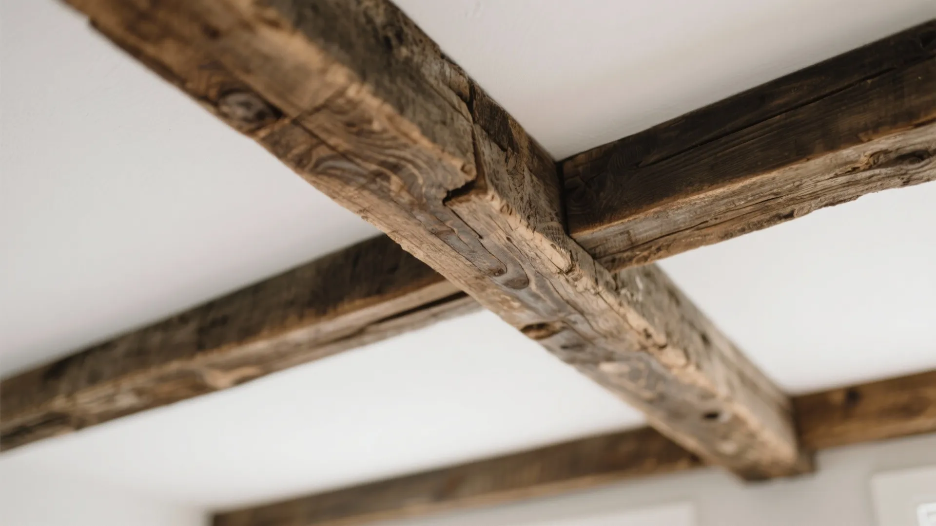 Rustic dark wood beams installed across a clean white ceiling inside a bright modern home