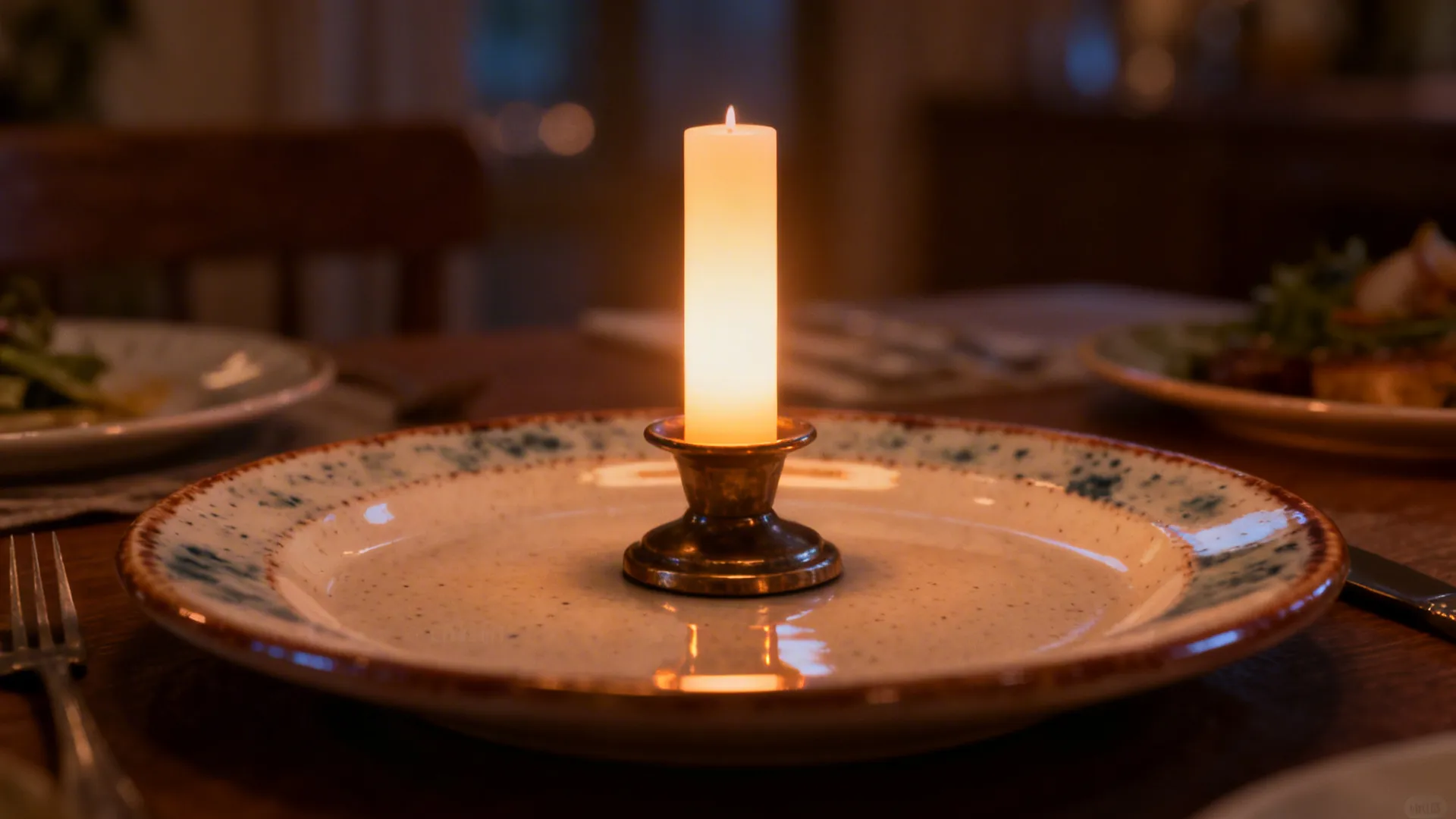 Short weighted candlestick and LED pillar on a ceramic plate creating warm ambient light.