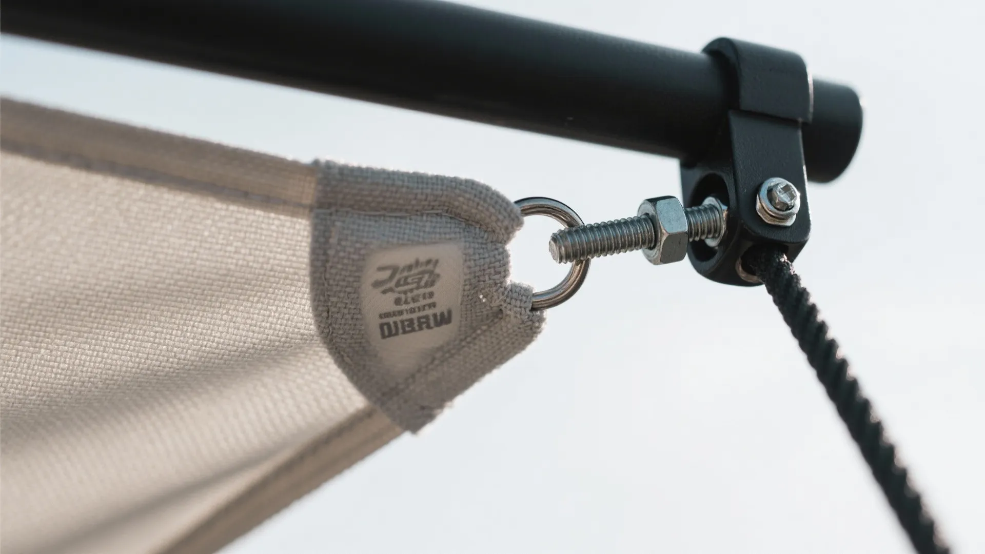 Close up view of metal screw and ring connecting white fabric shade to black support pole