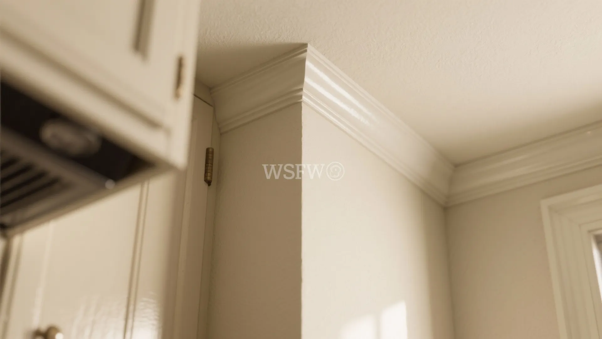 Close up view of white wall panel trim and ceiling corner in a beige kitchen