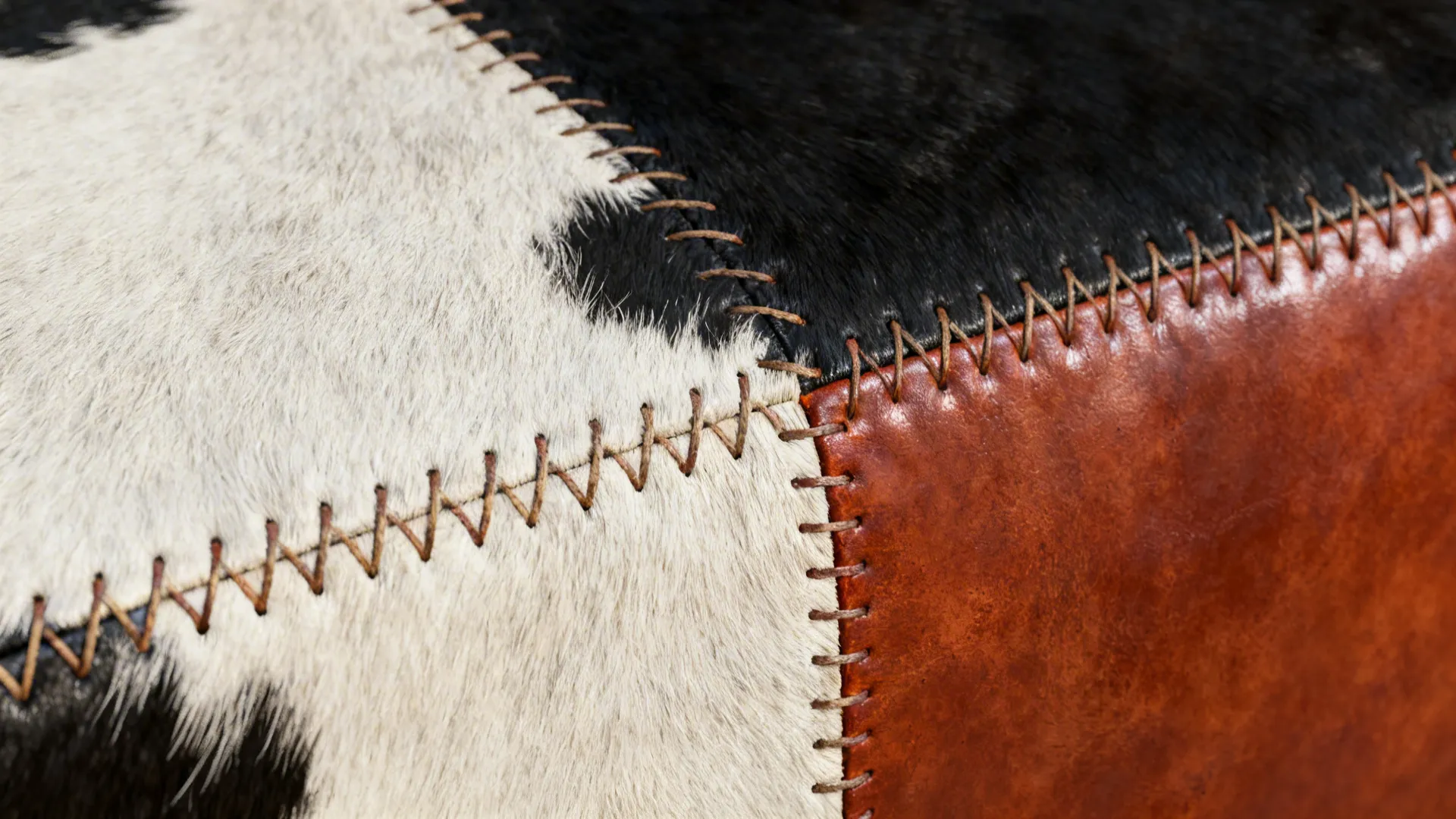 Macro of black-and-white cowhide next to a dyed rust panel showing stitch and texture contrast.