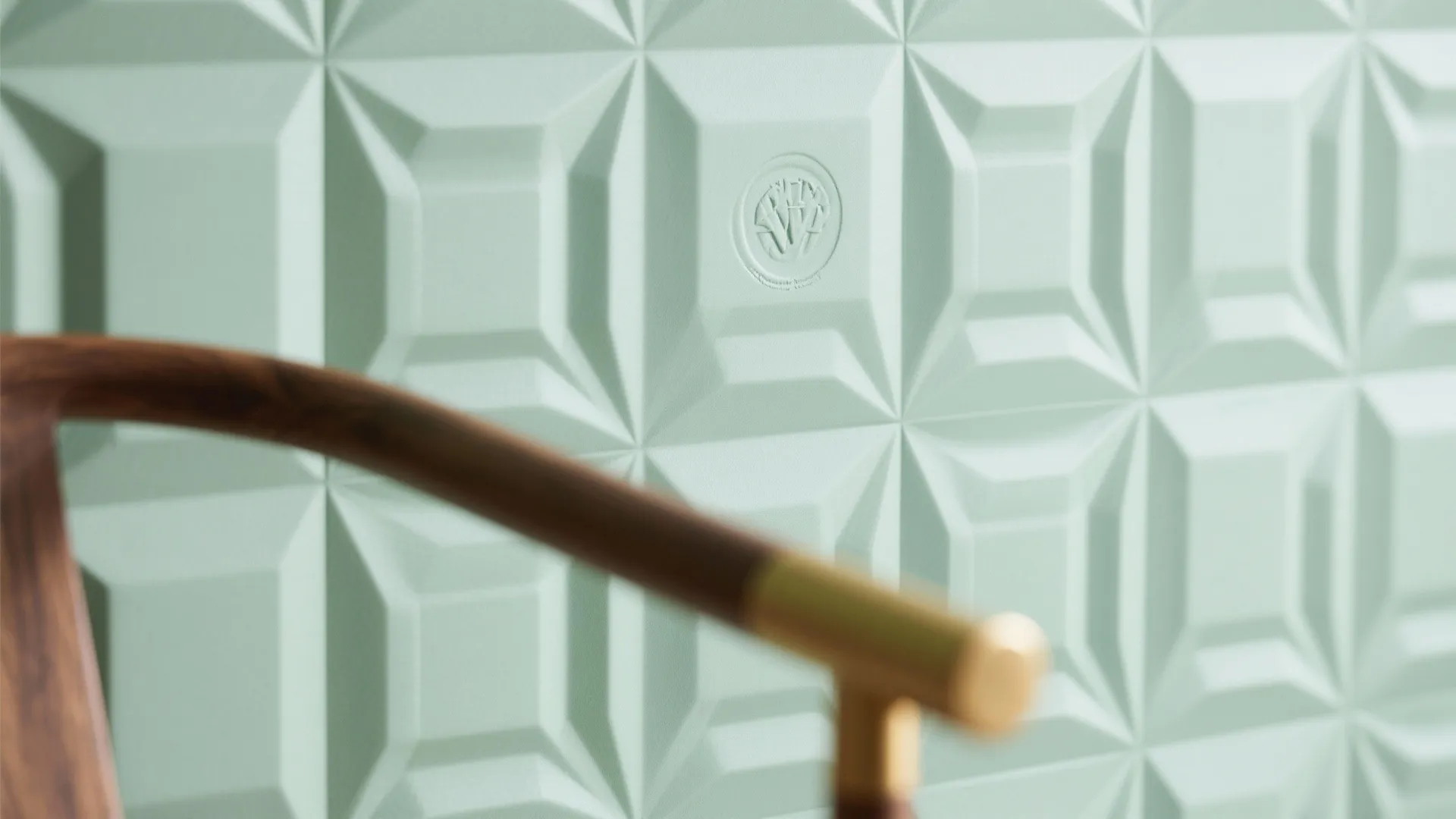 Light green wall panel with geometric square patterns and part of a wooden chair frame