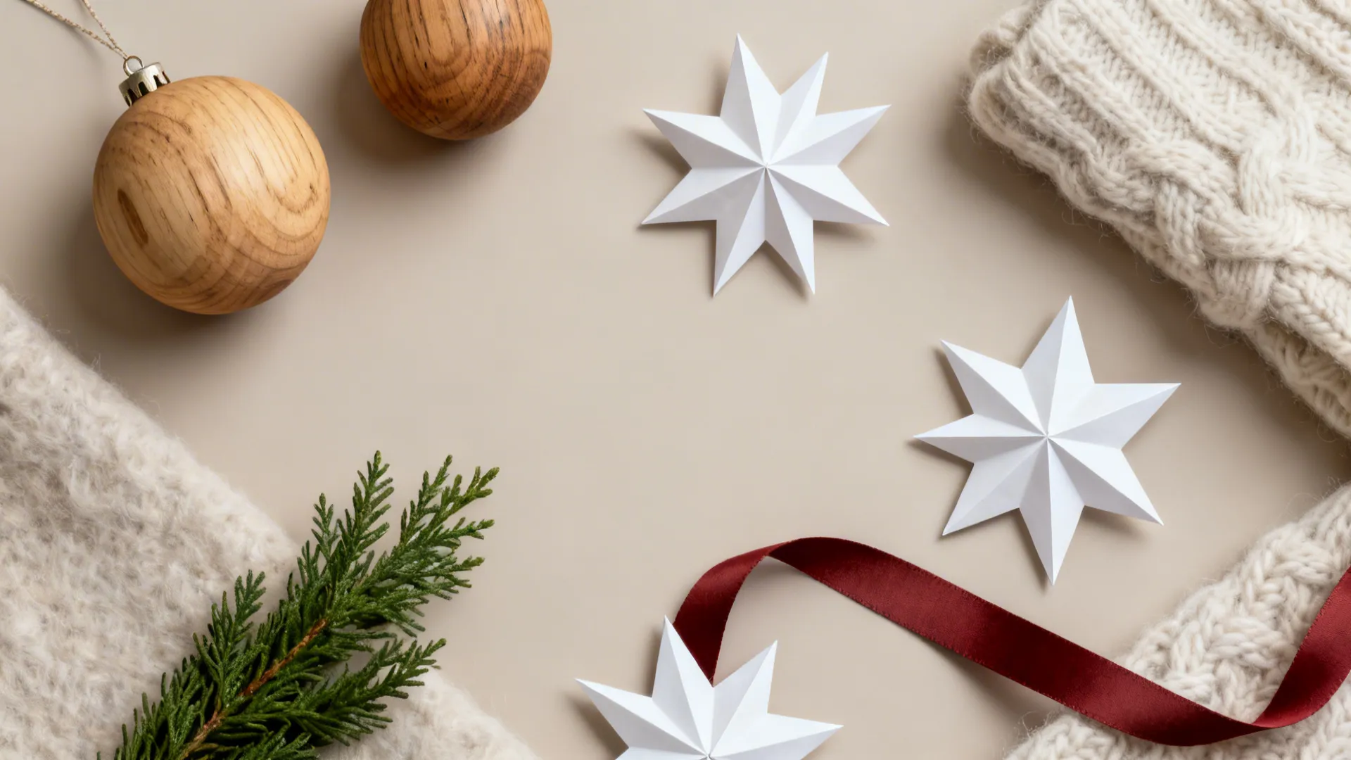 Flatlay of Scandinavian minimalist Christmas materials: wood, white paper stars, wool, and muted red accent.