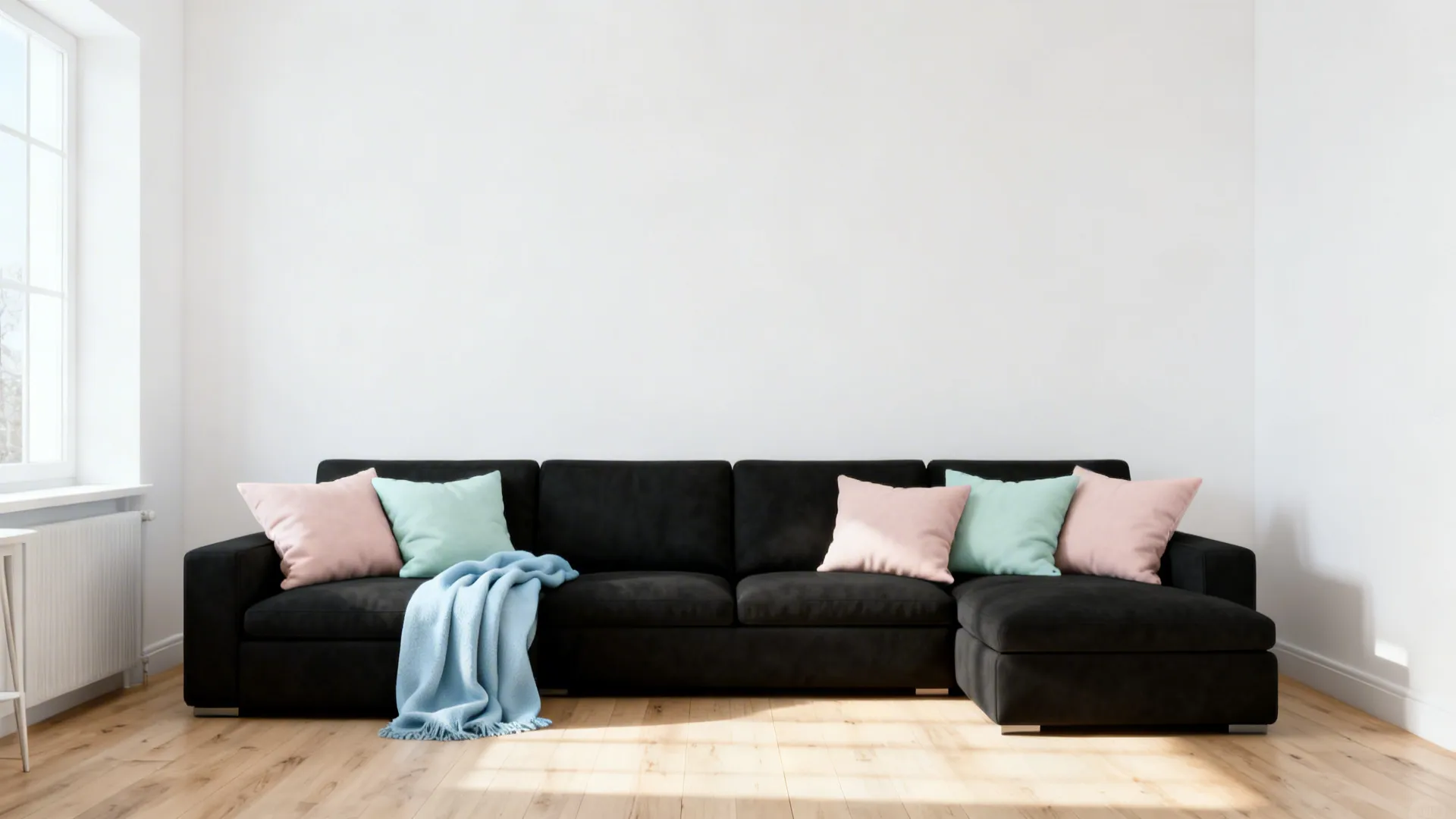 Scandinavian living room with a black sofa and soft pastel cushions amid white space.