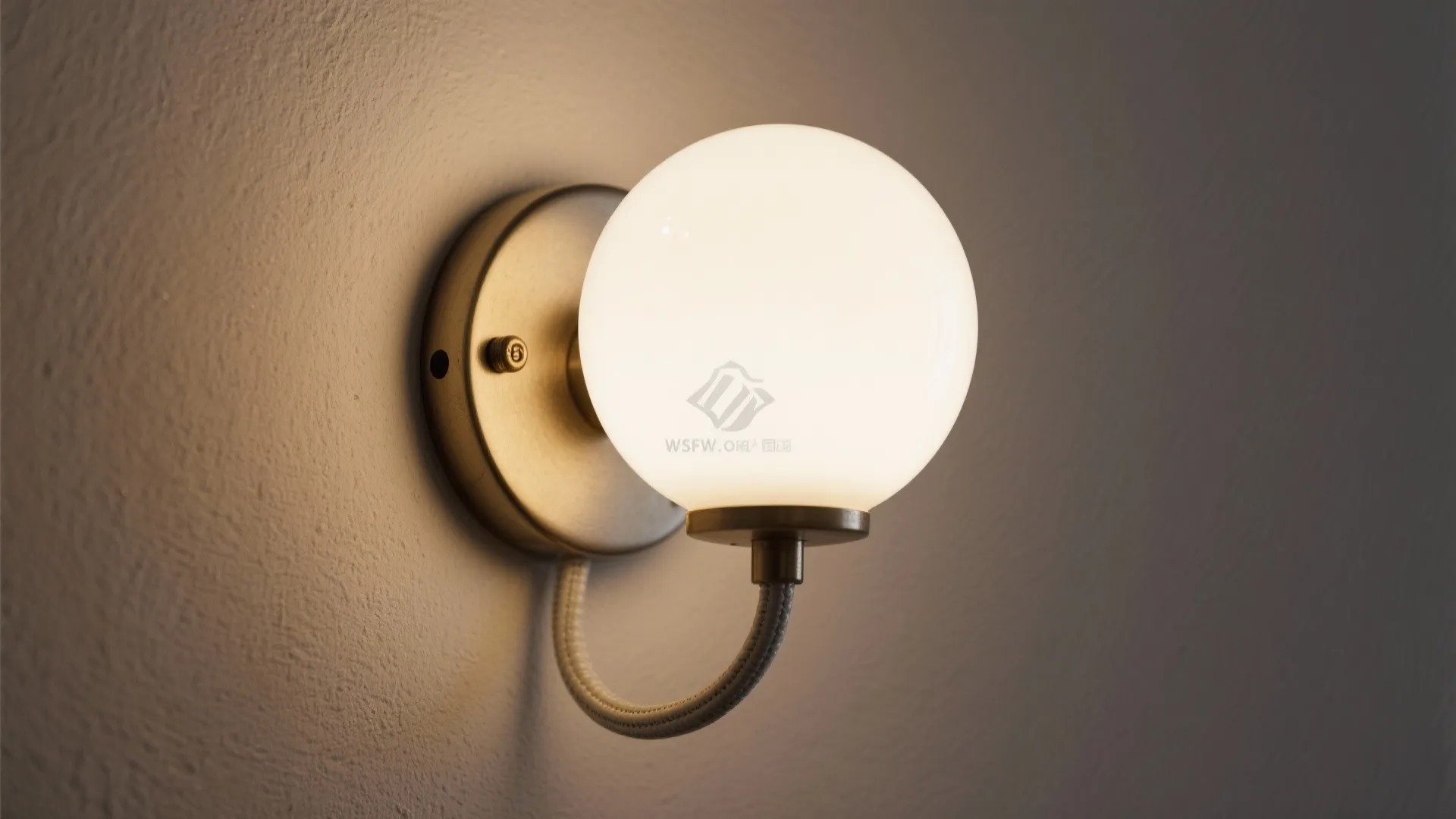 Macro of opal glass sconce with metal backplate and a painted cord cover on a matte wall.