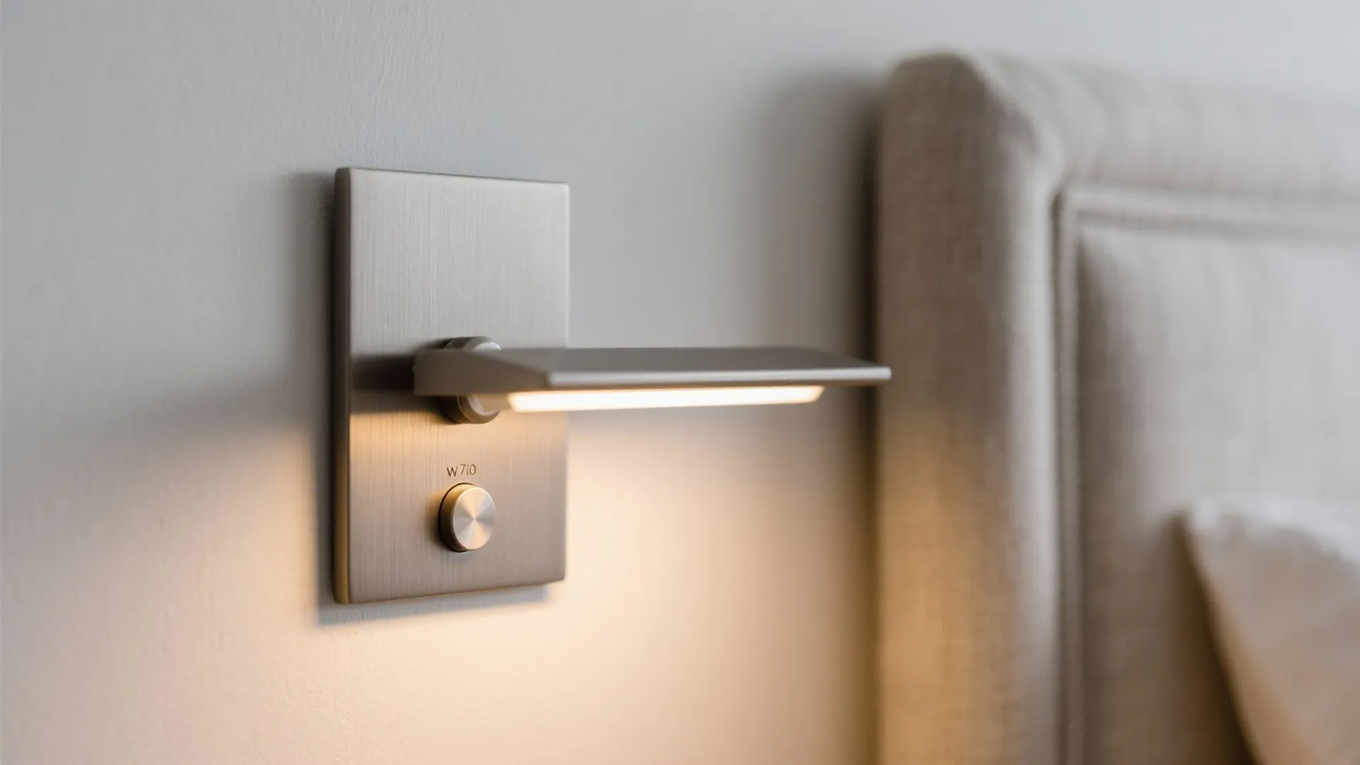 Close up of a metal wall light fixture with a dimmer switch next to a bed