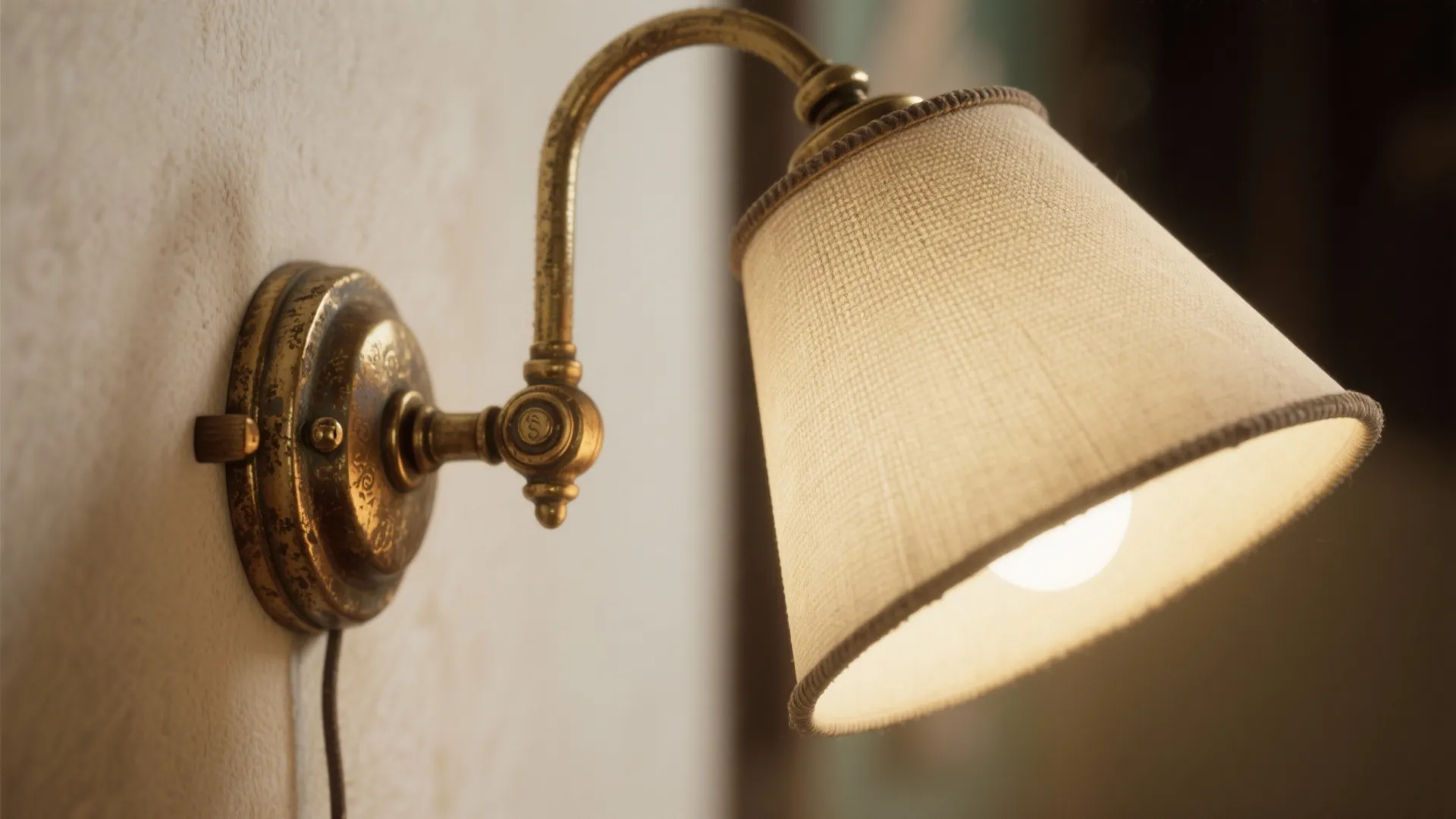 Macro detail of antique brass swing-arm sconce joint and linen shade texture.