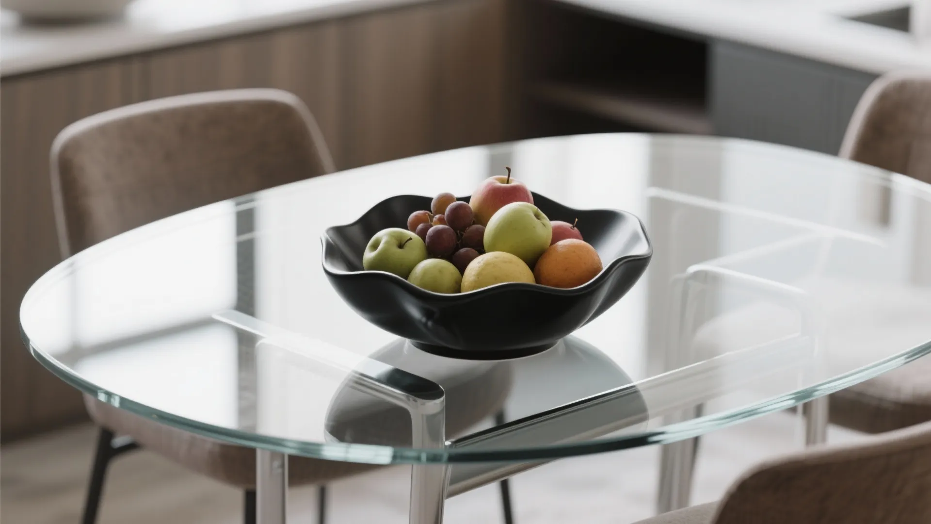 Black decorative bowl filled with fresh fruit sitting on a round glass dining room table